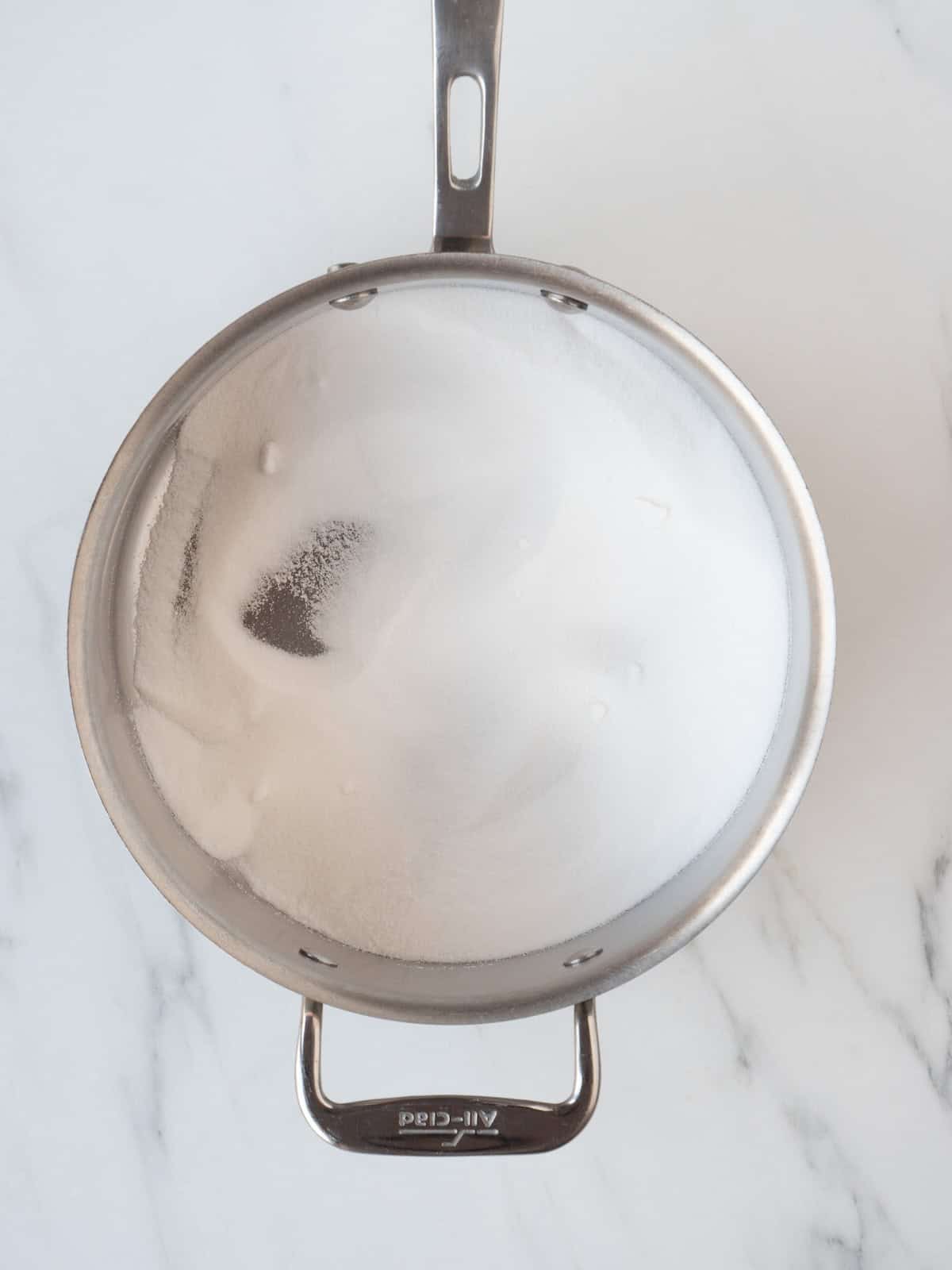 A saucepan with sugar and water being heated together.