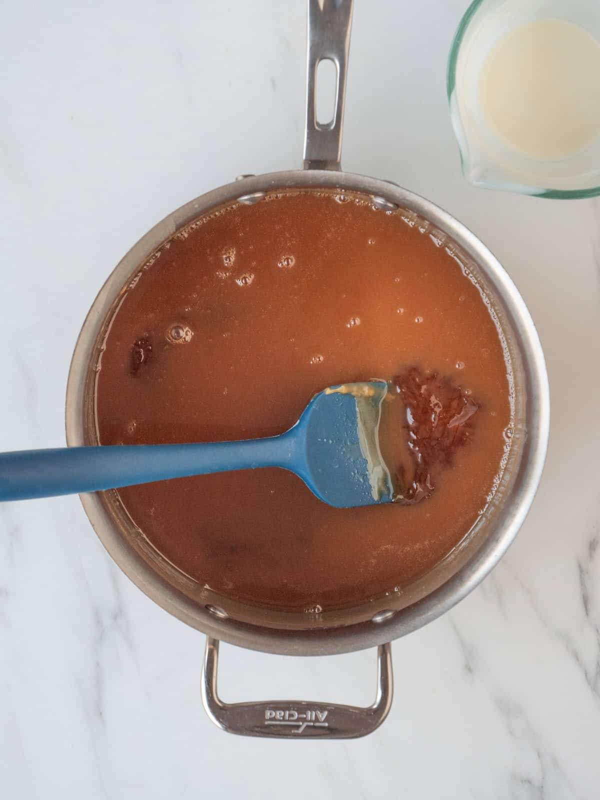 A saucepan with sugar and water heated together till it reaches a deep amber color, and cream added to make caramel sauce.