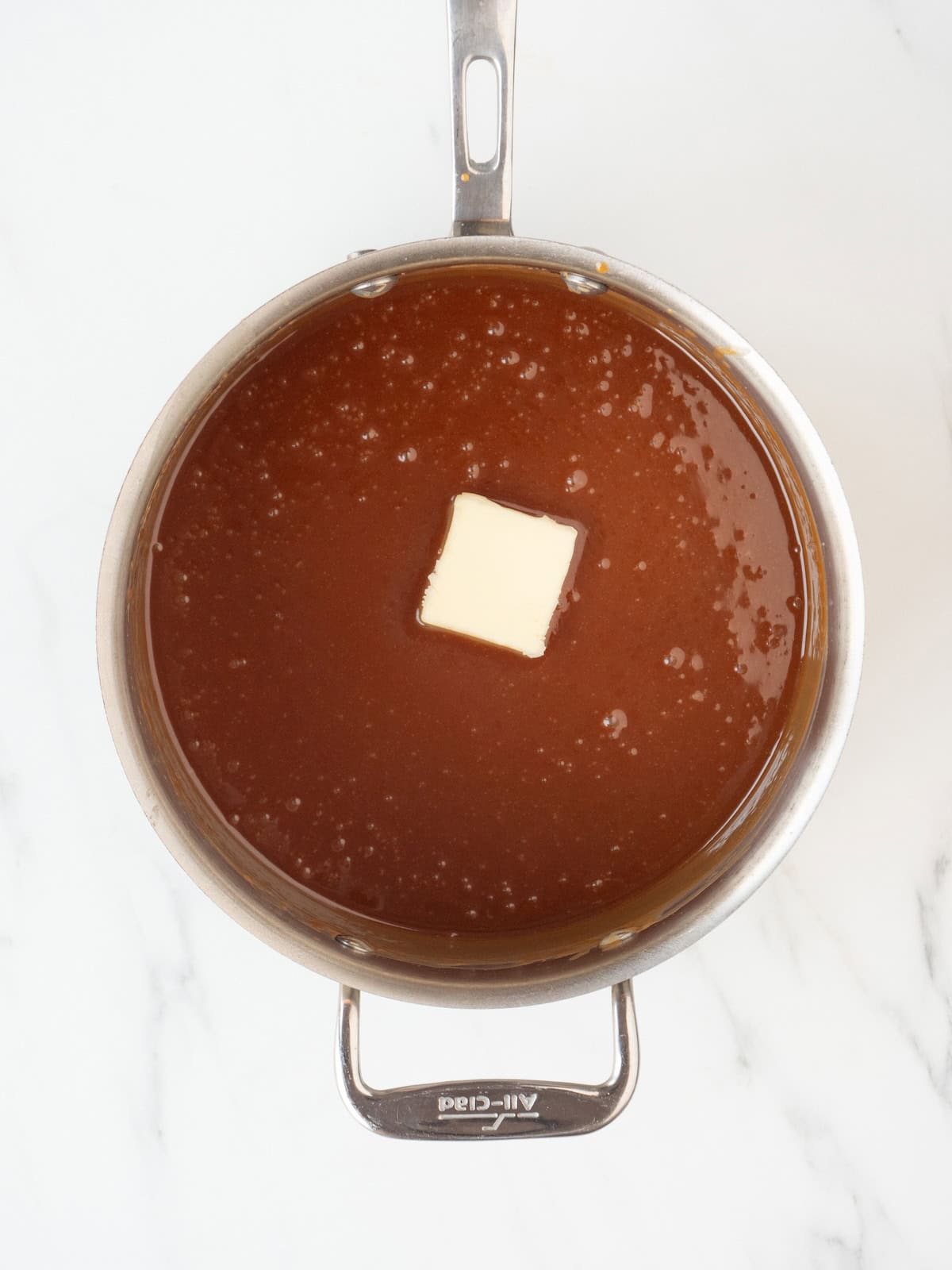 A saucepan with caramel sauce made from sugar, water and cream, and unsalted butter just added.