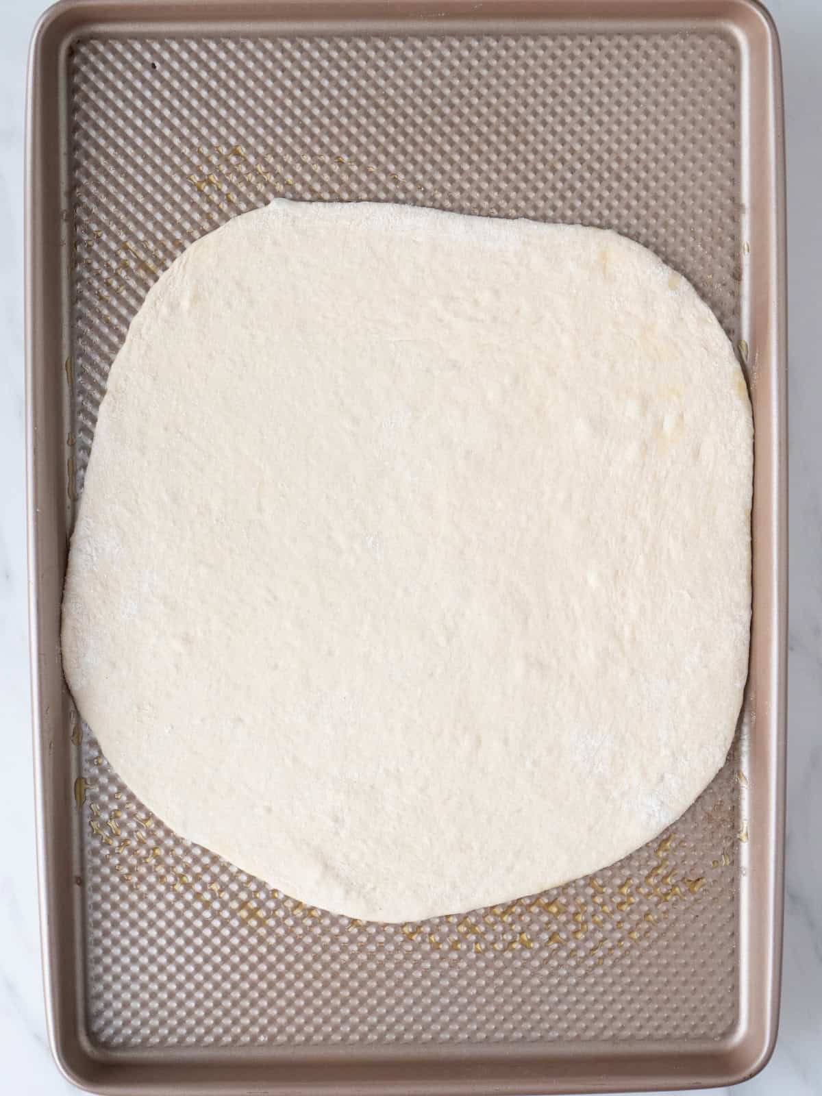 A baking sheet with a rolled out pizza dough.