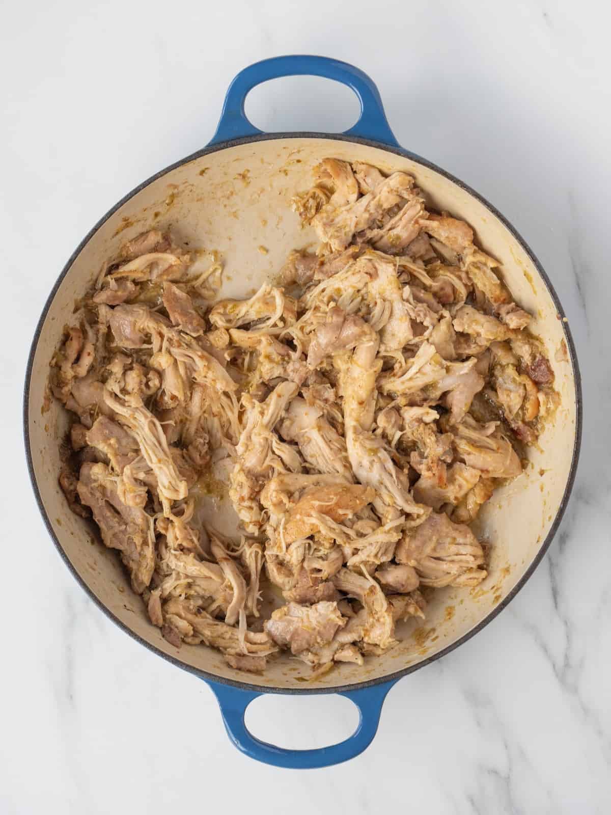 A dutch oven with shredded chicken verde.