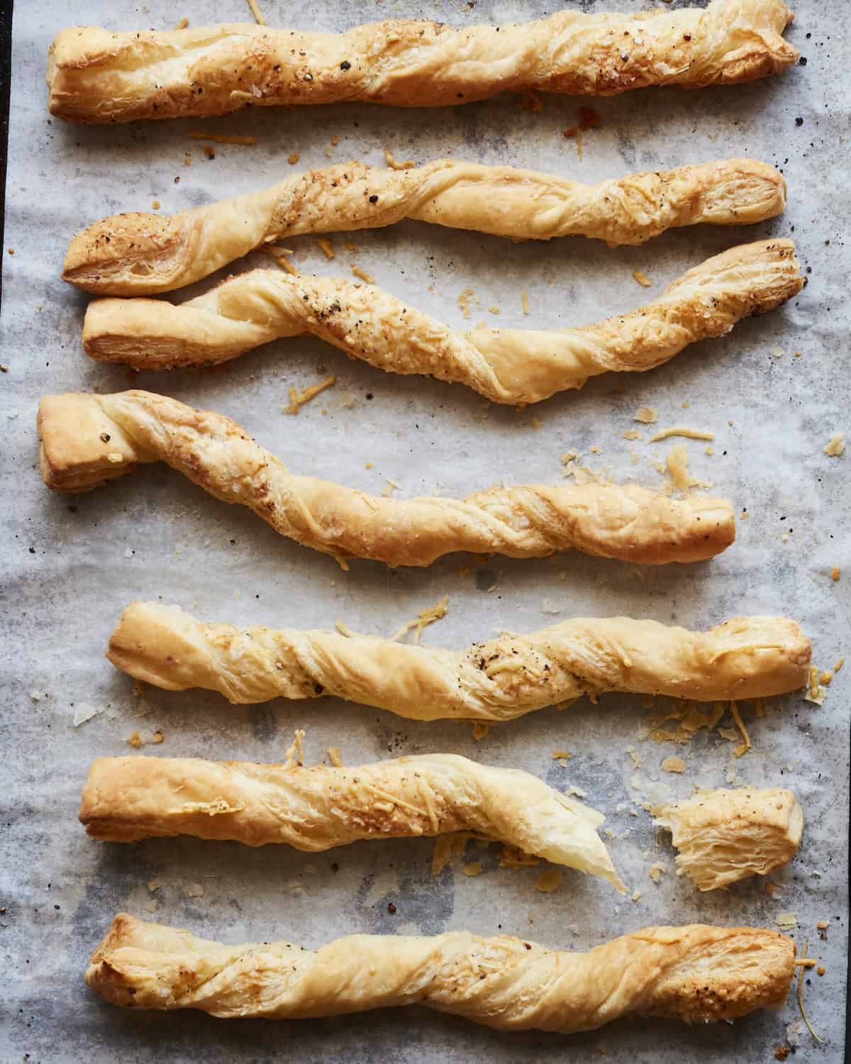An overhead shot of puff pastry cheese straws on parchment paper.