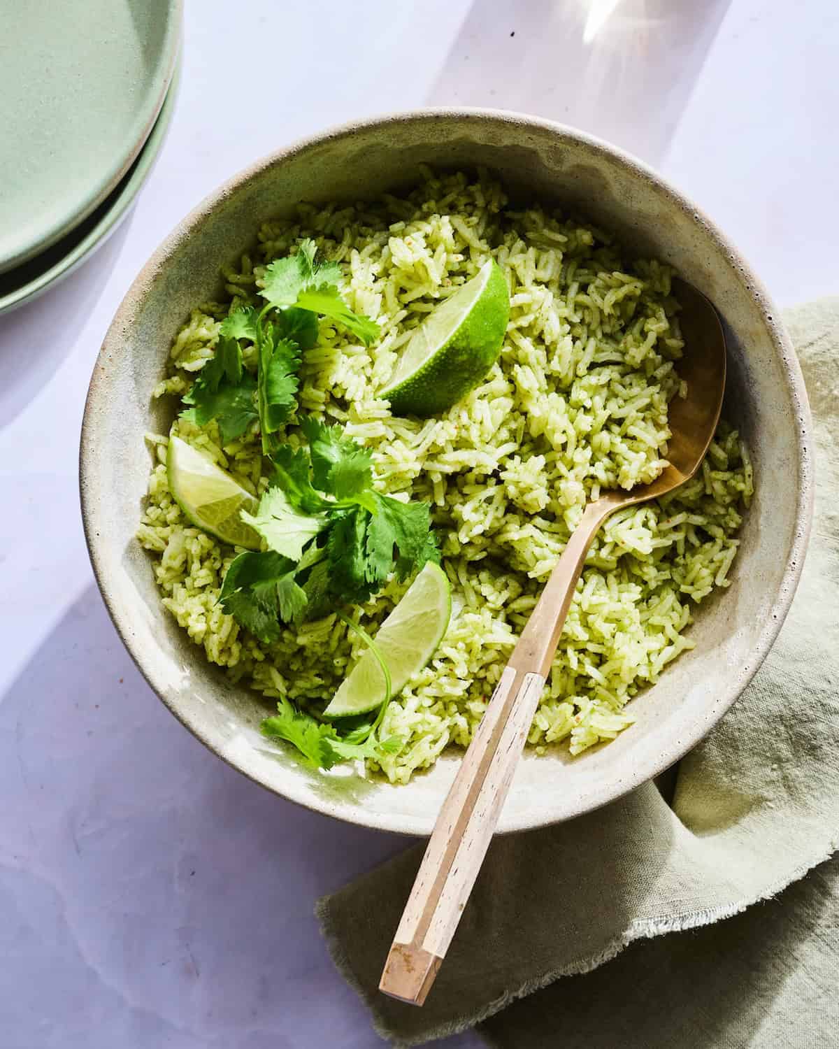Cilantro Rice in a serving bowl with some extra cilantro on top and some lime wedges. 