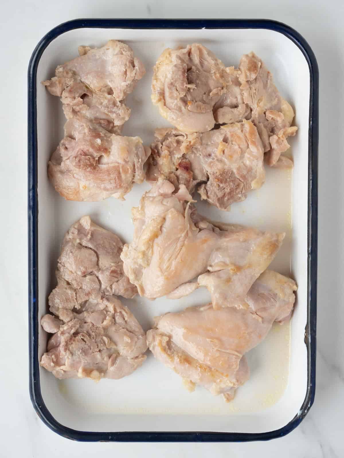 A rectangular dish with browned chicken thighs.