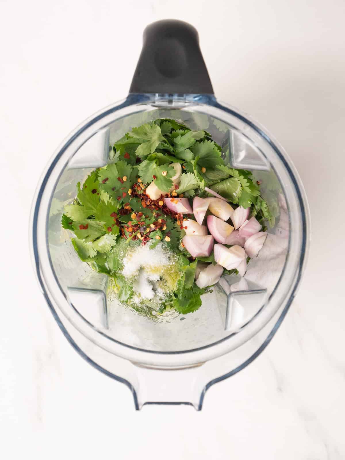 A blender jar with all the ingredients to make cilantro vinaigrette.