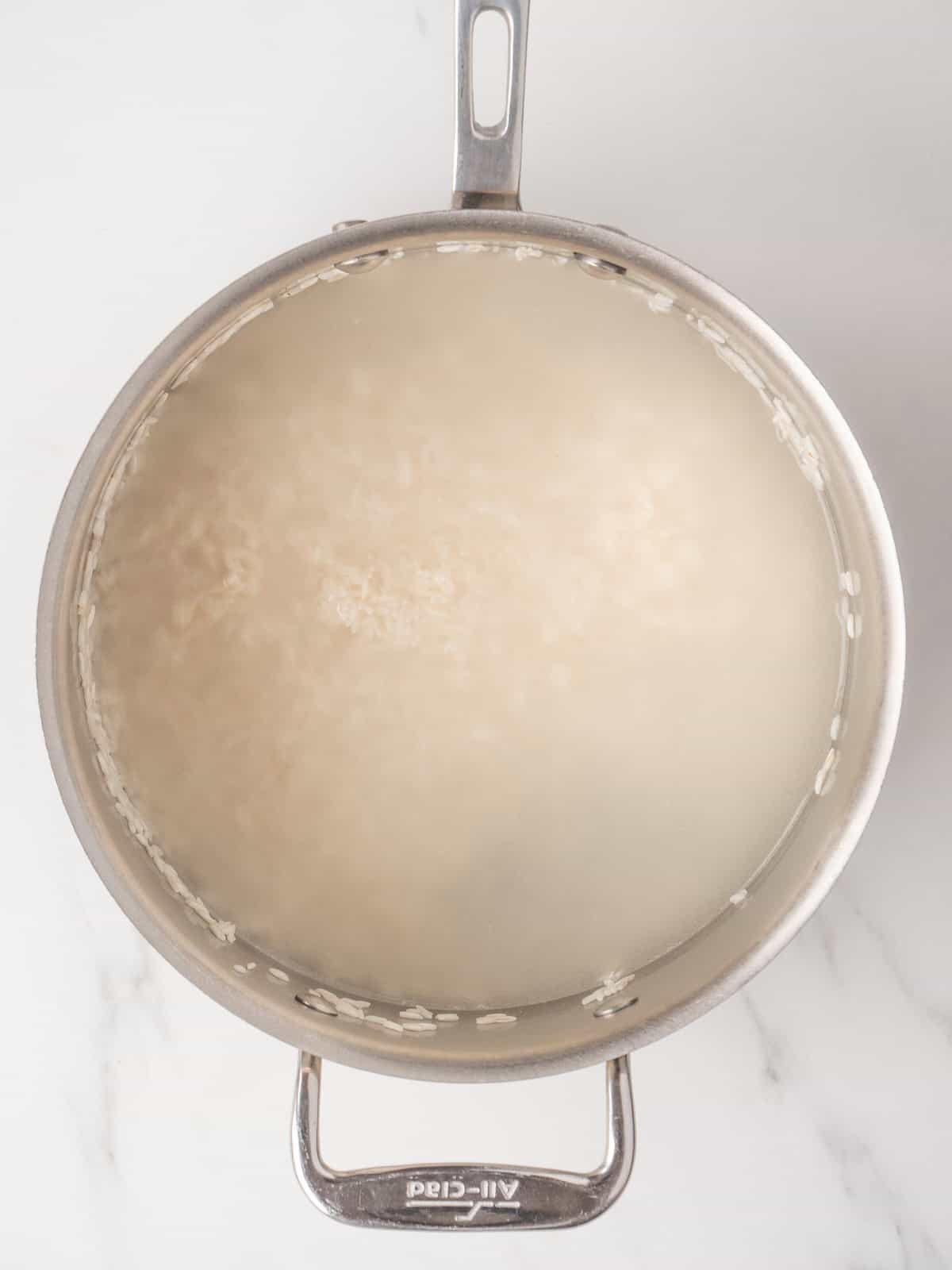 A saucepan with rice and water being boiled together.