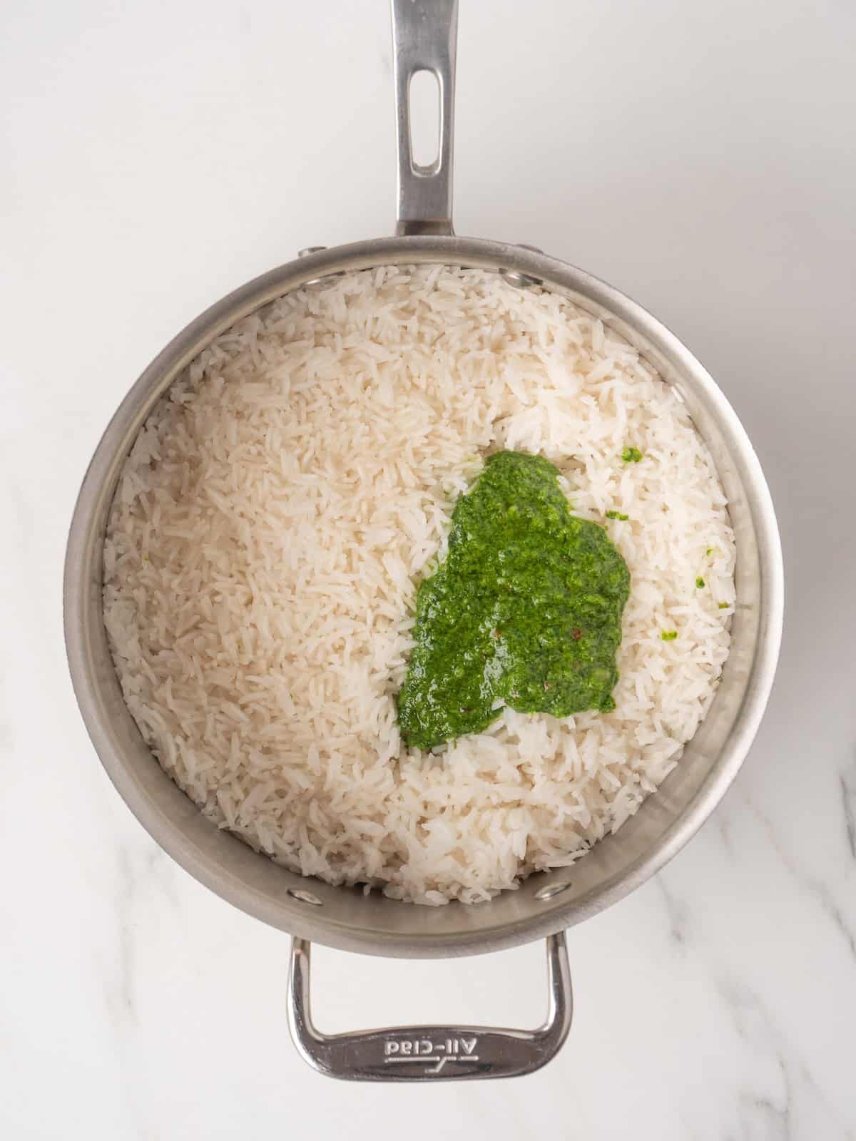 A saucepan with cooked rice, and cilantro vinaigrette just added.