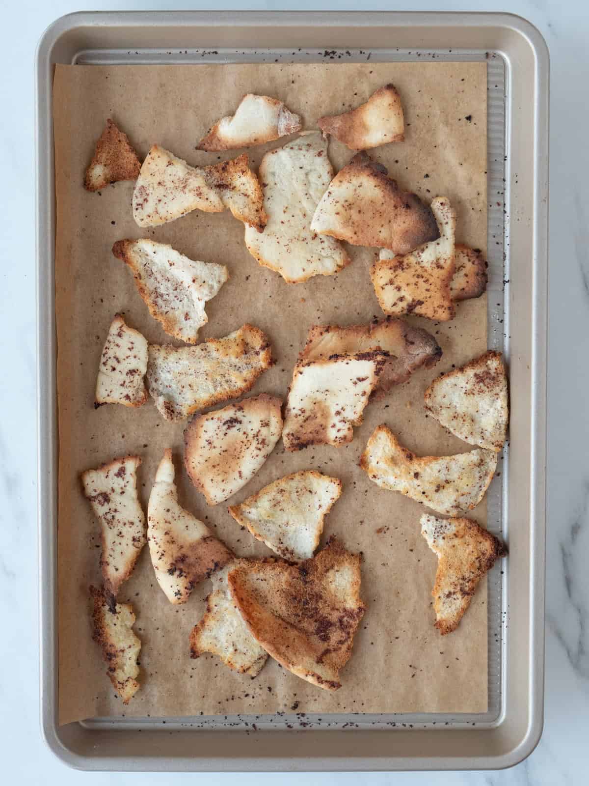 A parchment paper lined baking sheet with toasted pita fresh from the oven.