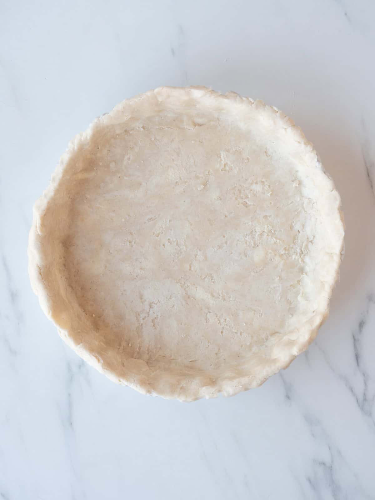 Rolled out pie dough laid on to a pie pan and pressed in.