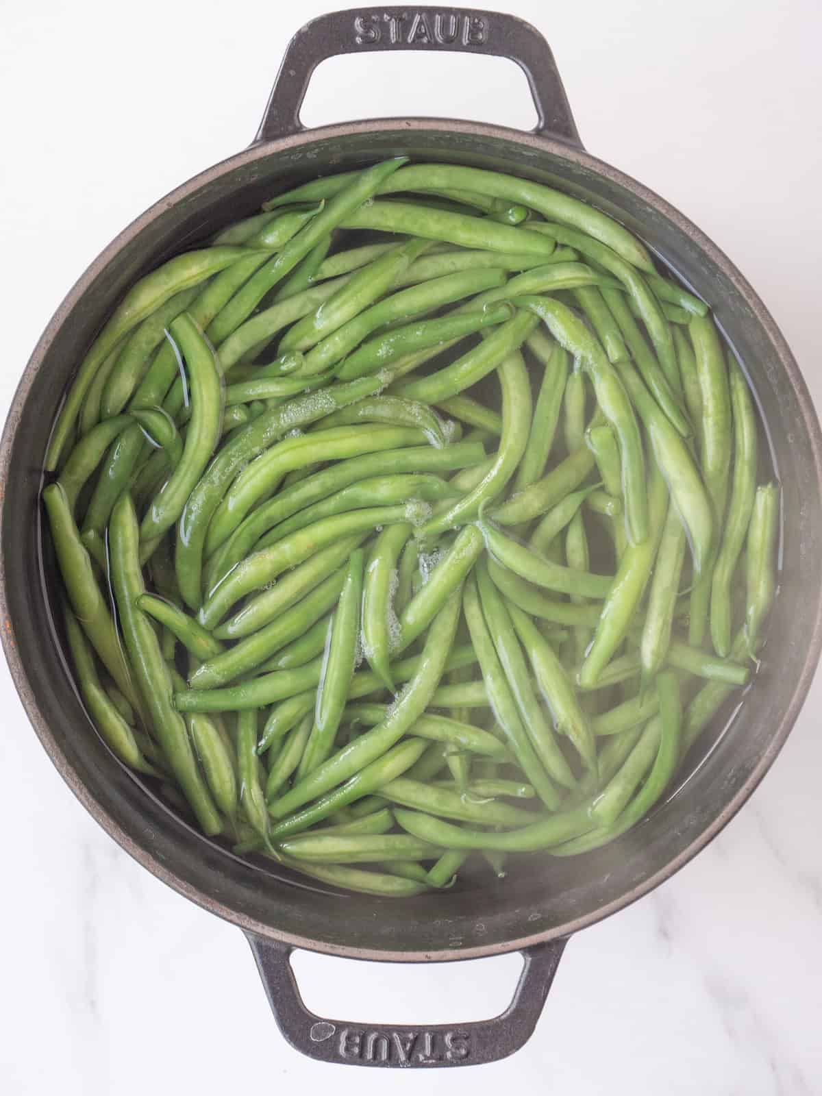 A large pot of boiling water with green beans being cooked.