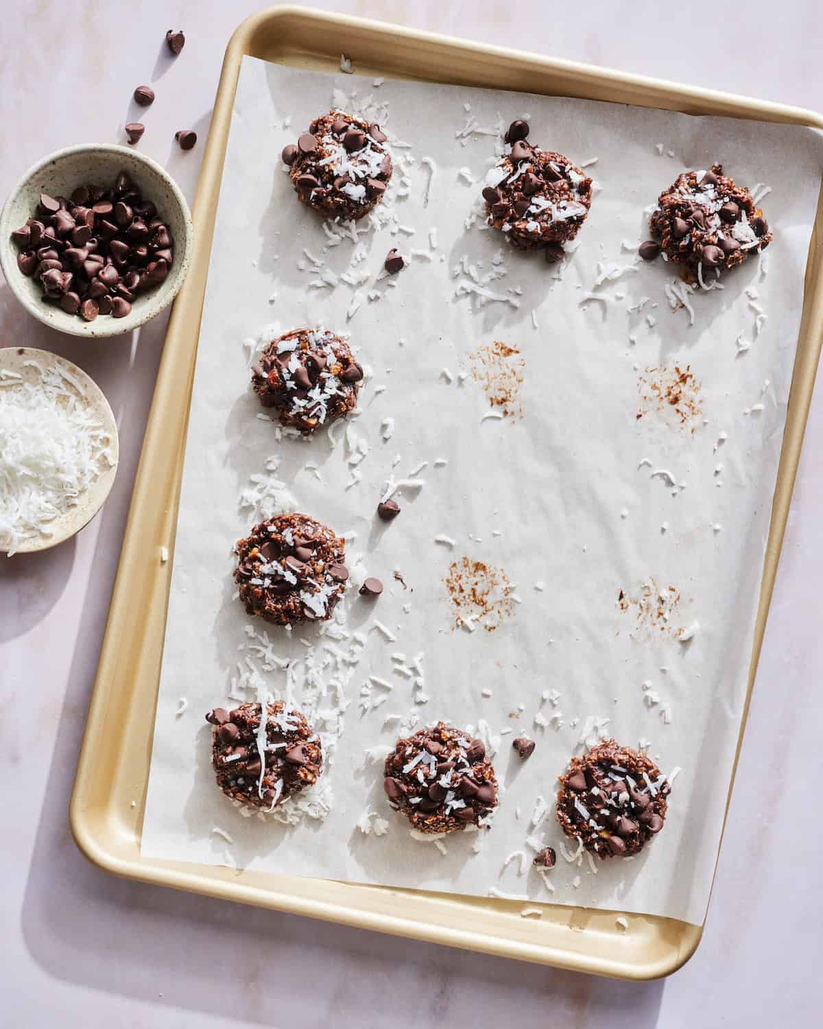 No Bake Double Chocolate Chip Cookies with almond butter and coconut flakes on a baking sheet