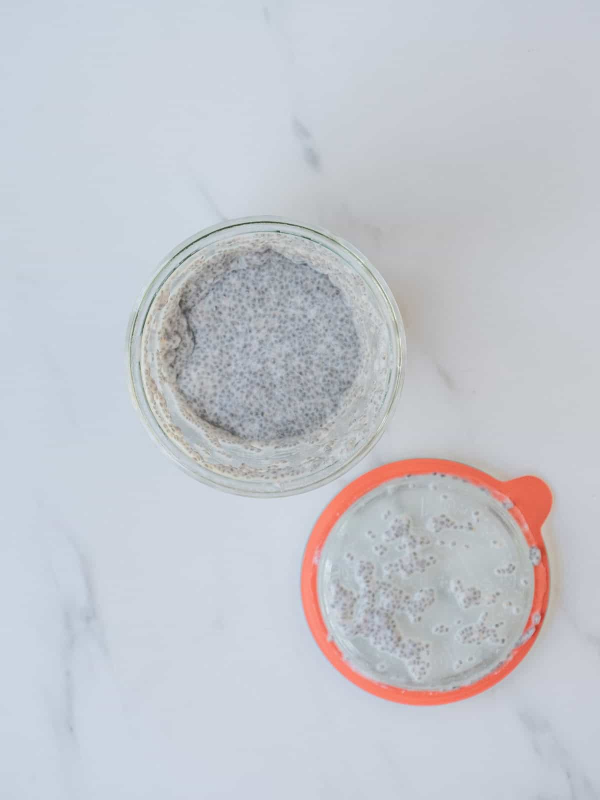 A mason jar with chia pudding ingredients shaken together and the lid on the side.