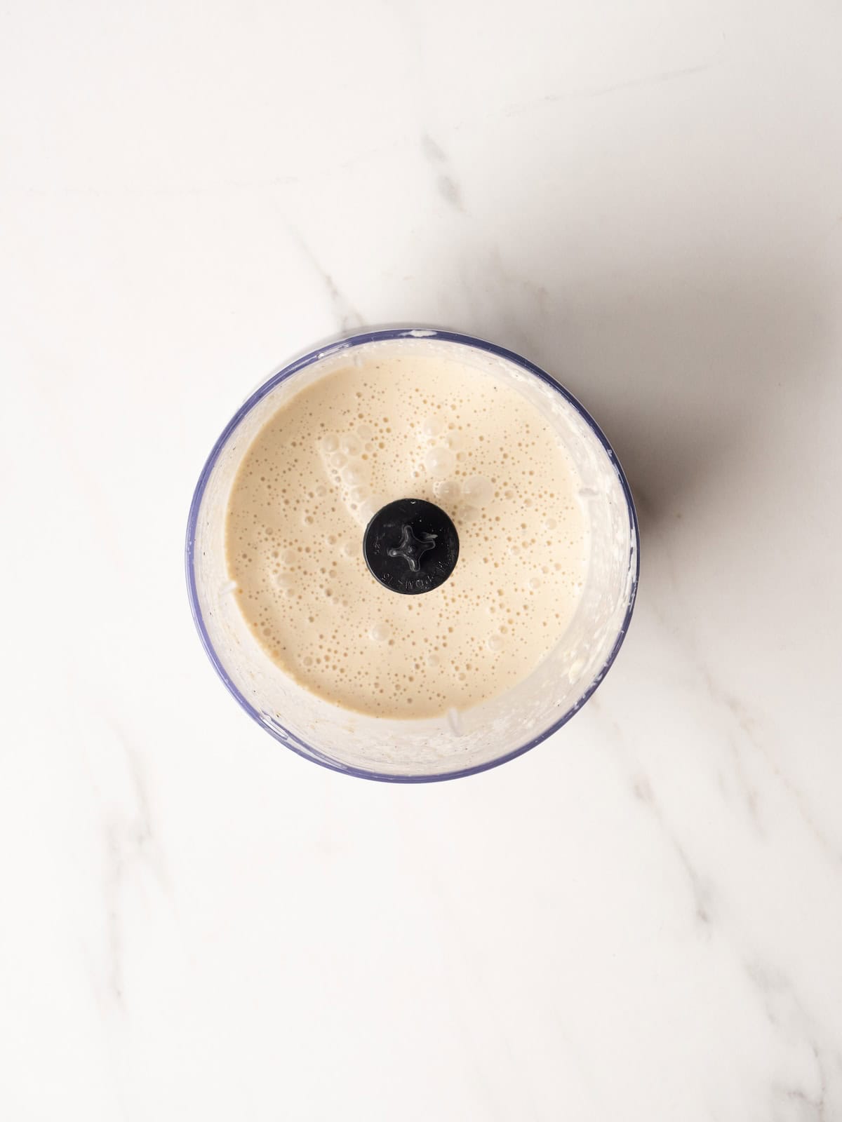 Food processor jar with caesar salad dressing.