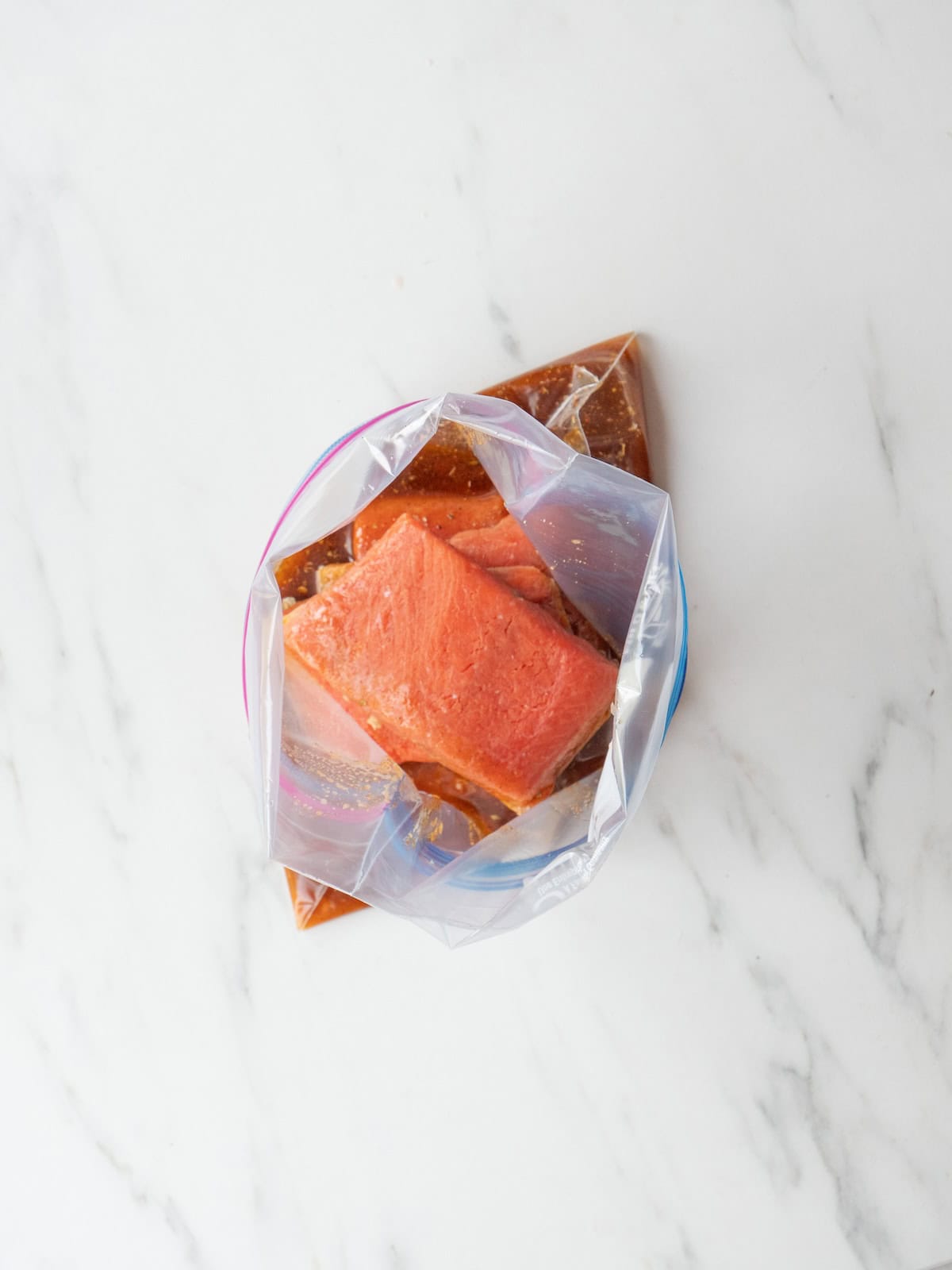 A zip-top bag with salmon in a marinade.