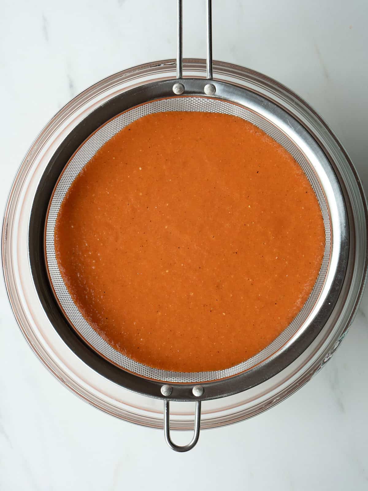 Strained orange soup in a sieve.