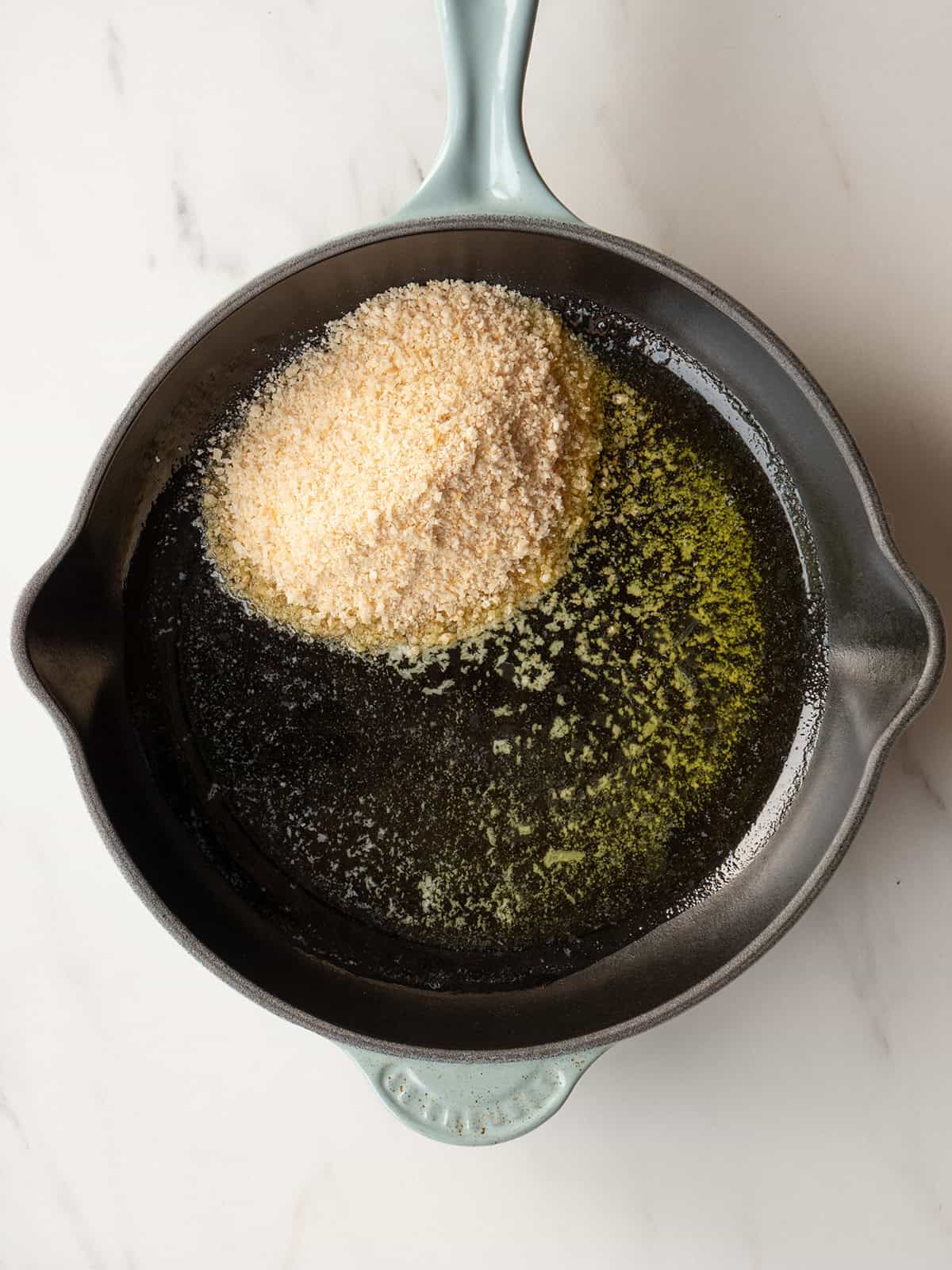 Oil and breadcrumbs in skillet
