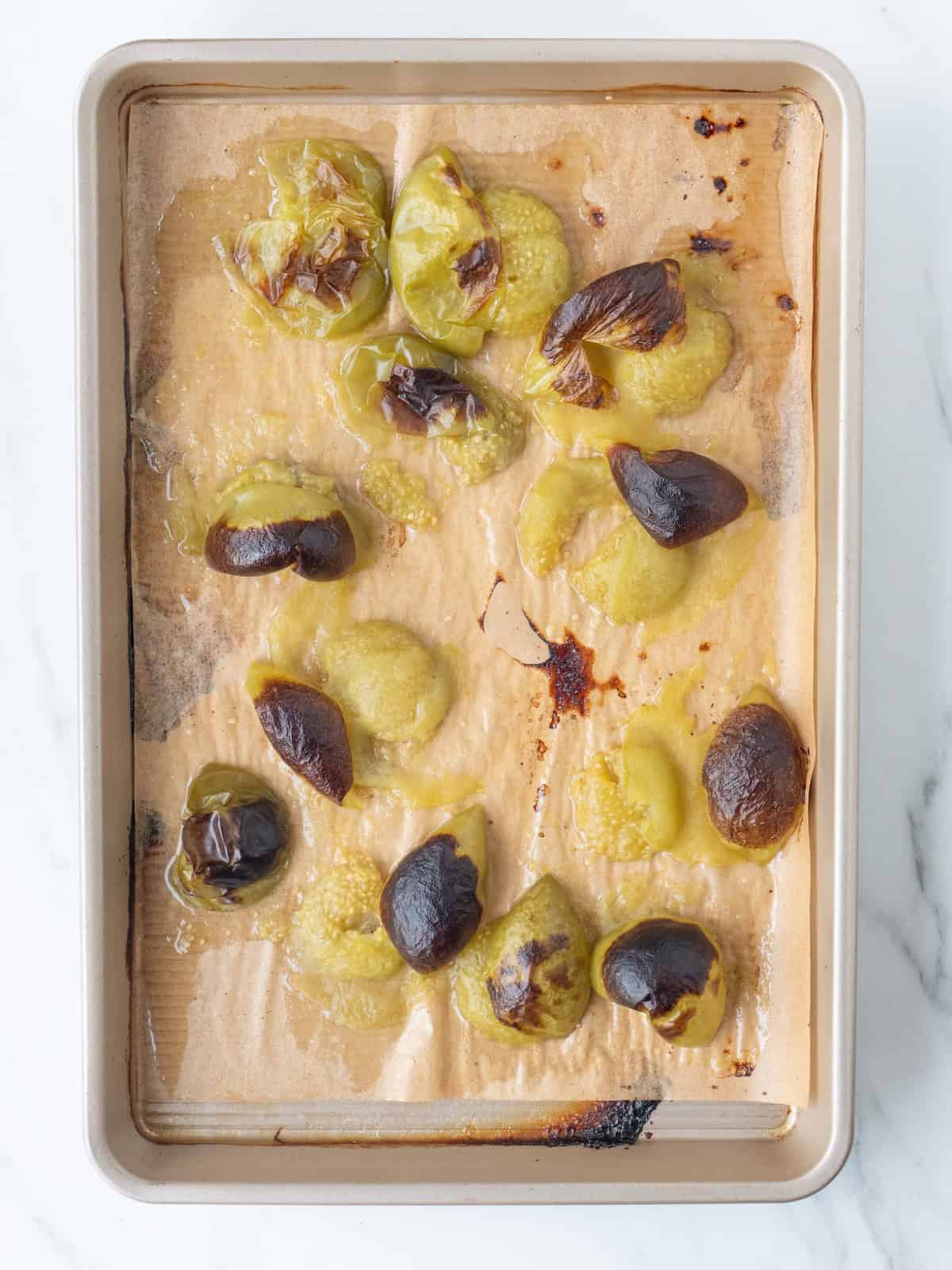A sheet pan lined with parchment paper, with roasted tomatillos.