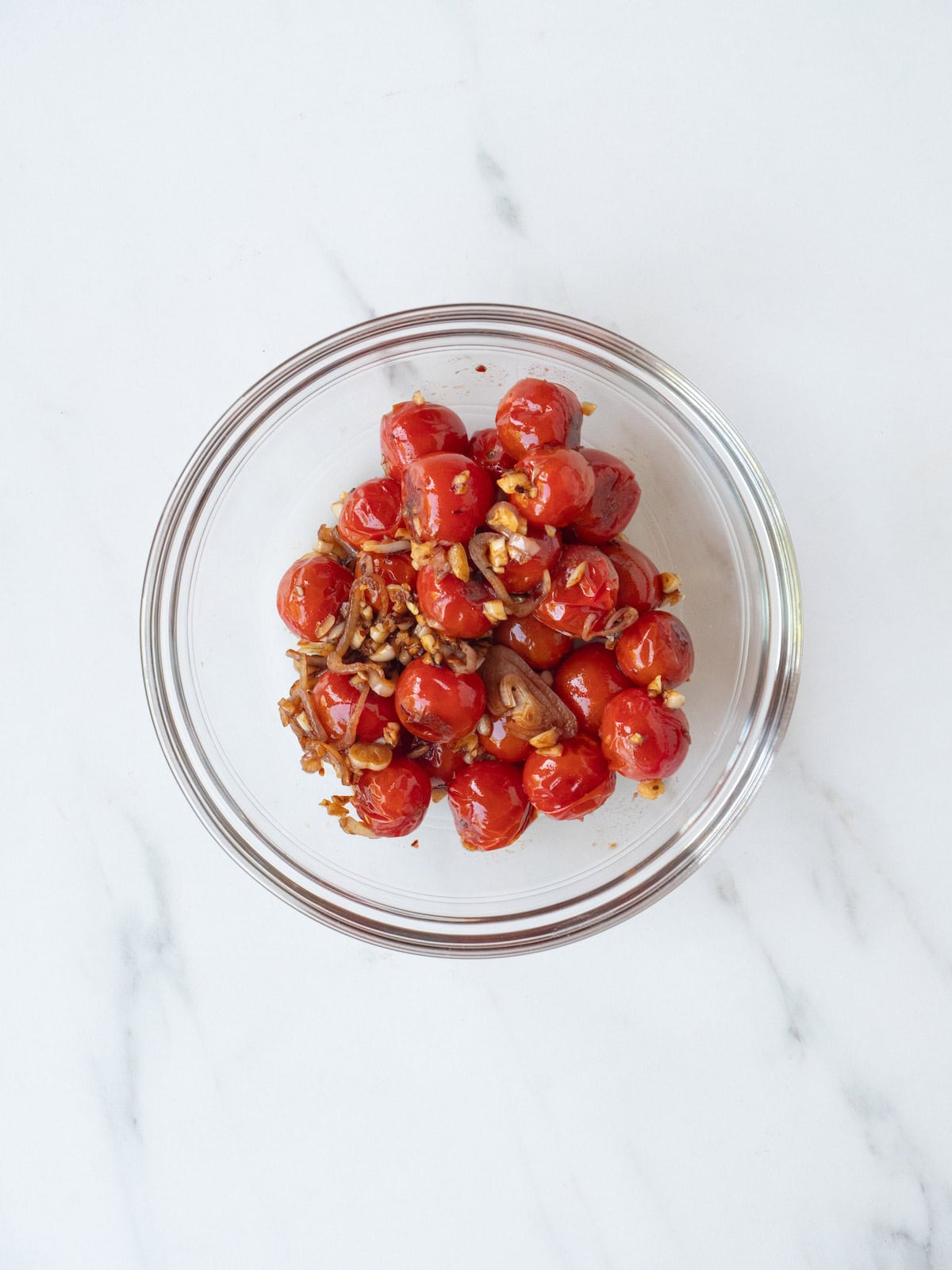 A small glass bowl with the blistered cherry tomato mixture to make tomato basil gnocchi.