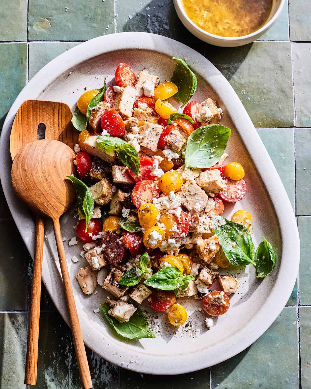 Creamy Feta Dressing over a pile of fresh tomatoes, chicken and basil