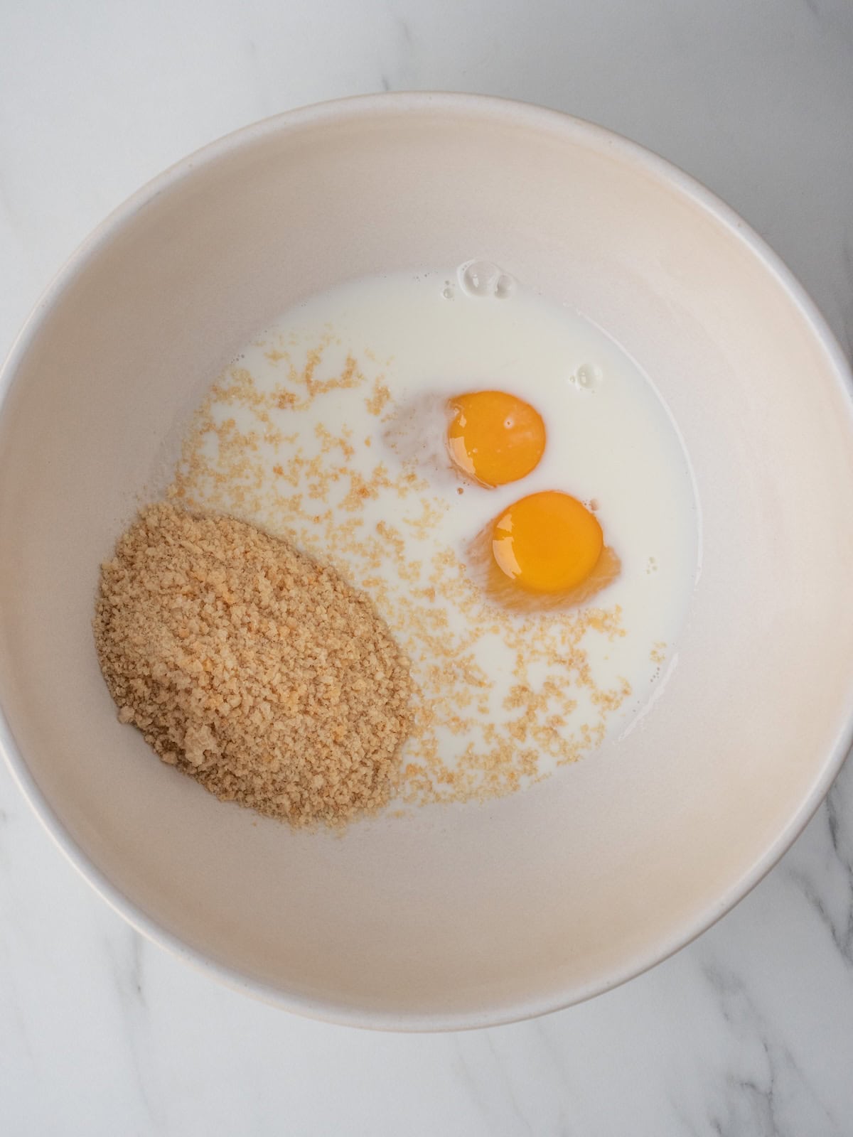 A mixing bowl with milk, eggs and breadcrumbs to make a mixture for the meatloaf.