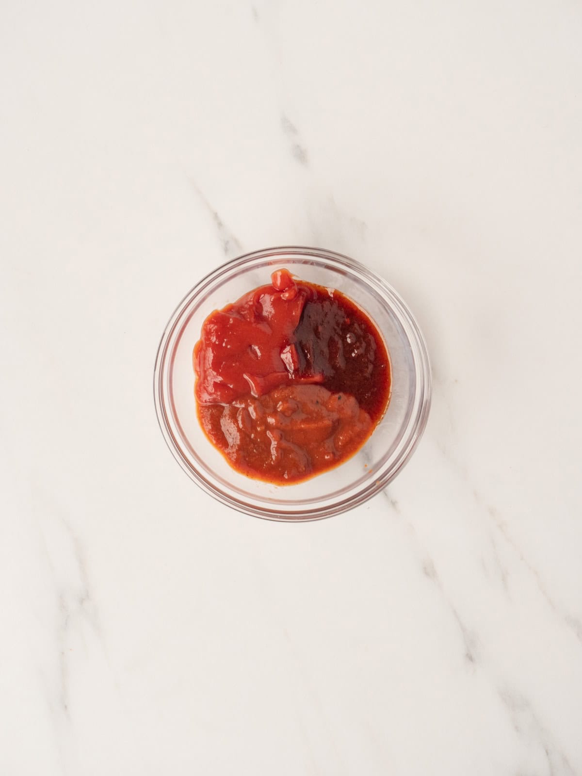 A small mixing bowl with BBQ sauce, ketchup and adobo sauce.