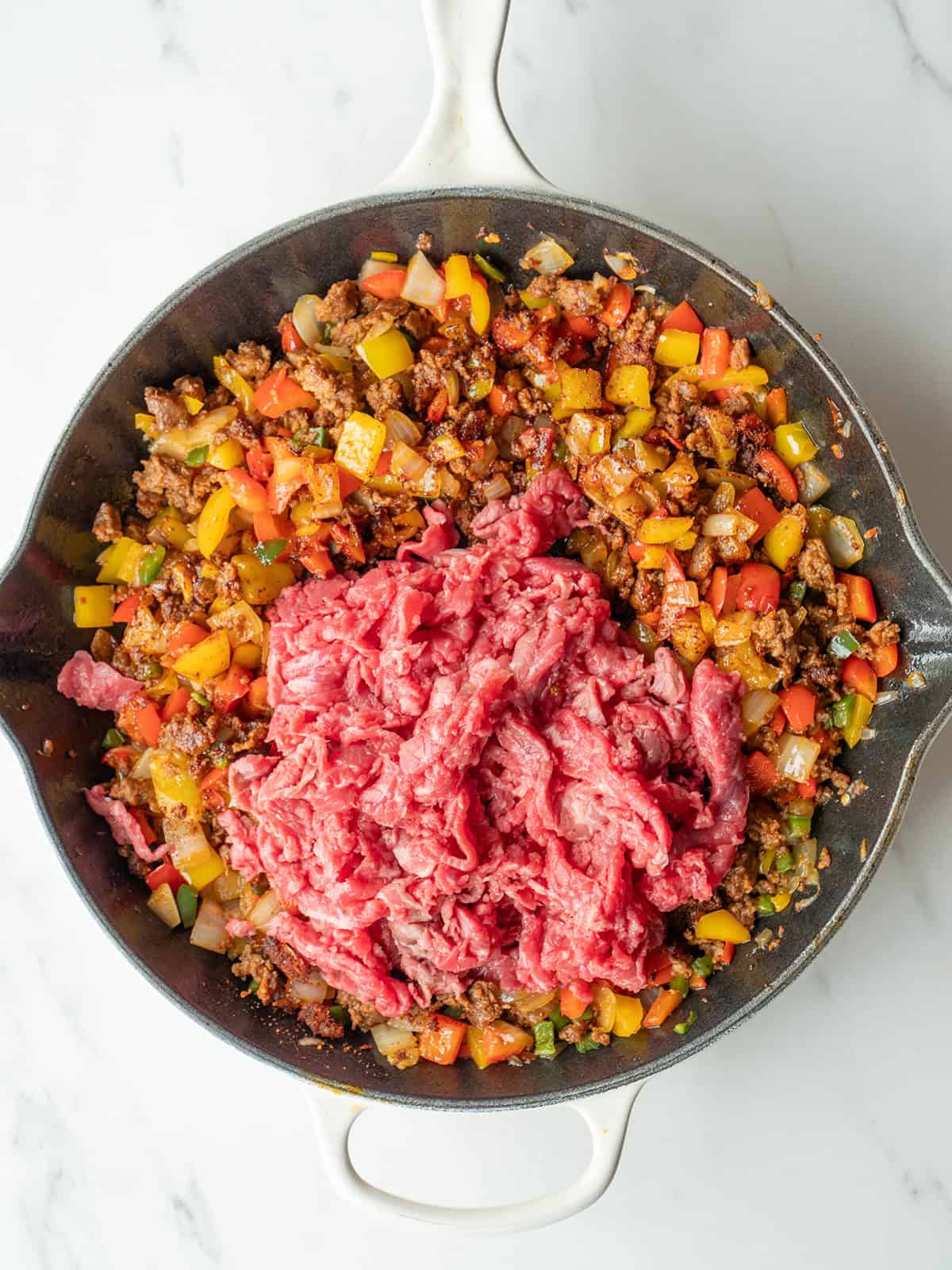 Shaved meat and colorful vegetables in skillet
