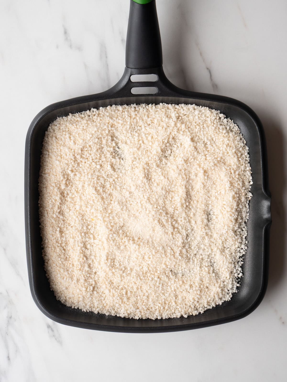 A non-stick skillet with panko breadcrumbs being toasted.