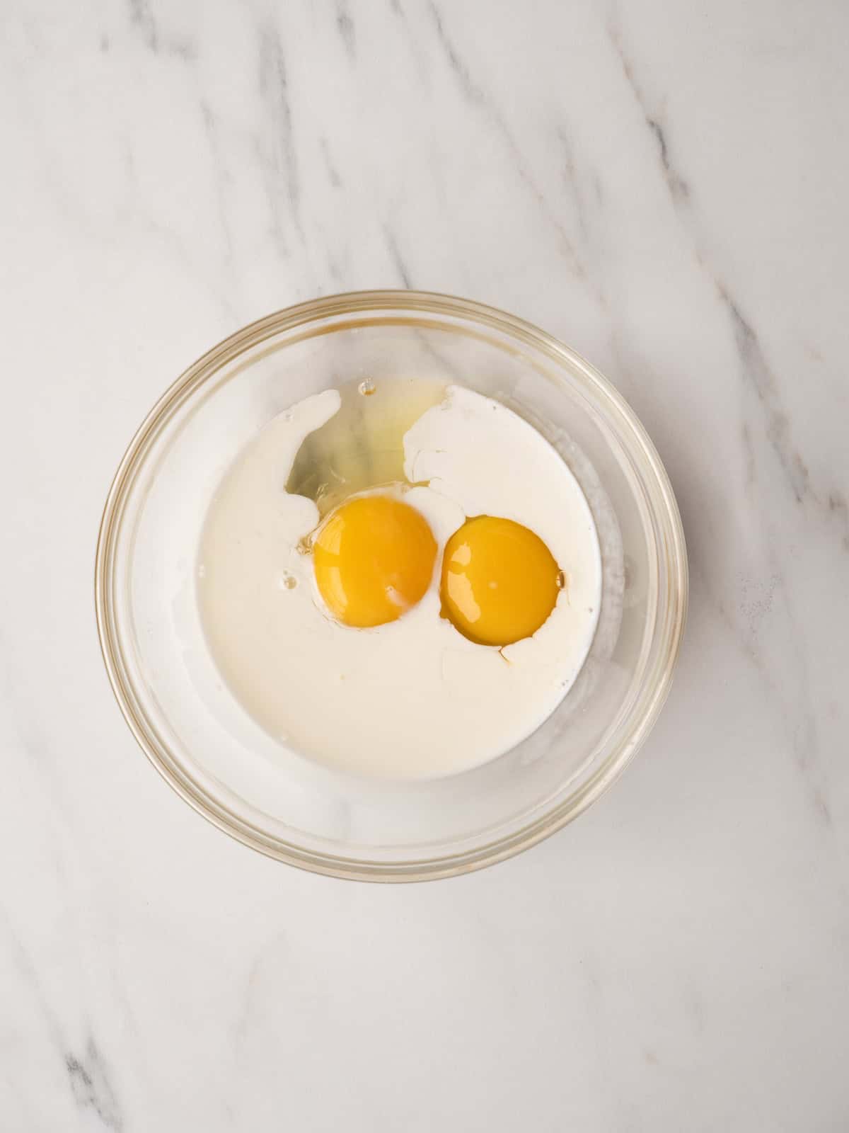 A mixing bowl with eggs and milk mixed together.