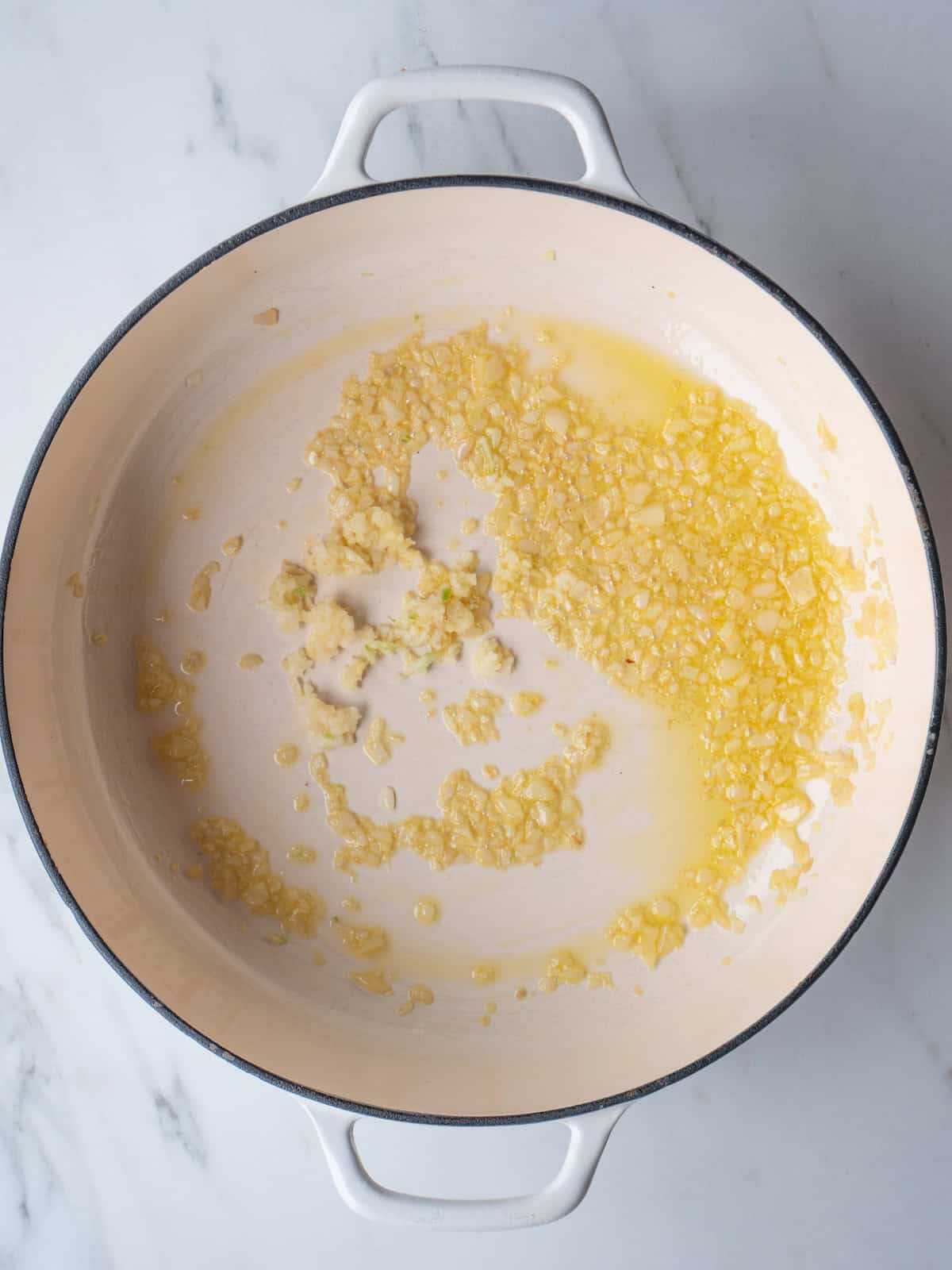 A dutch oven with sautéed shallots and minced garlic added.