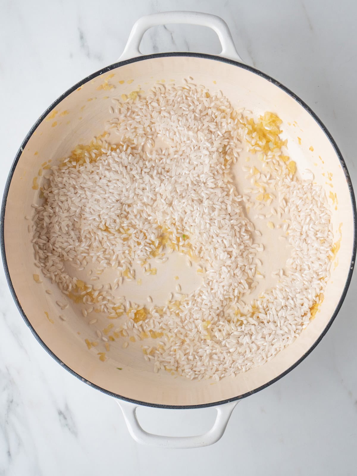 A dutch oven with arborio rice added to some sautéed shallots and garlic.