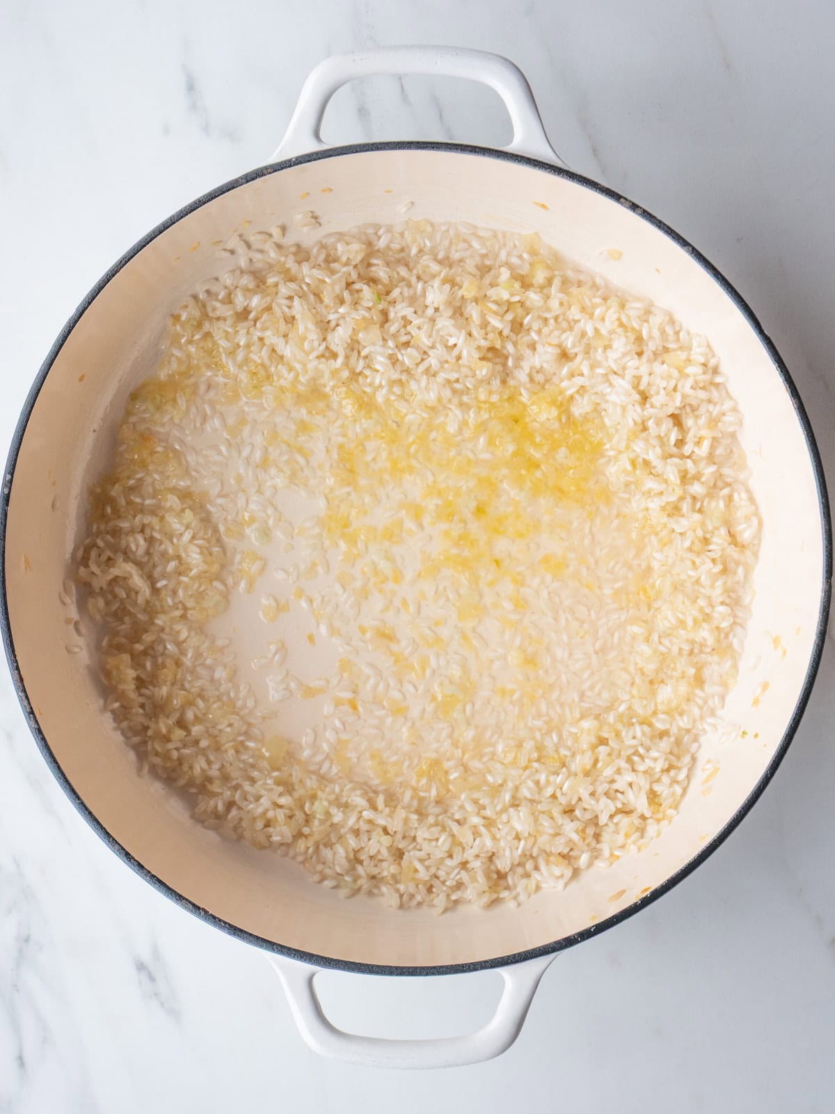 A dutch oven with arborio rice being toasted.