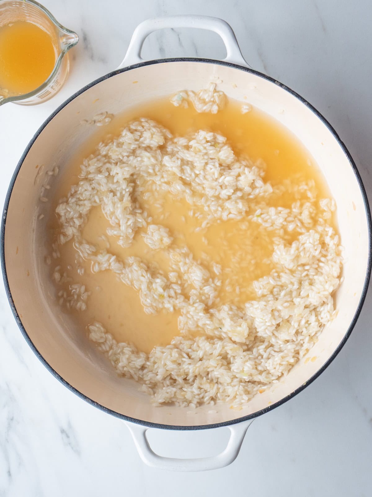 A dutch oven with toasted arborio rice and white wine added.