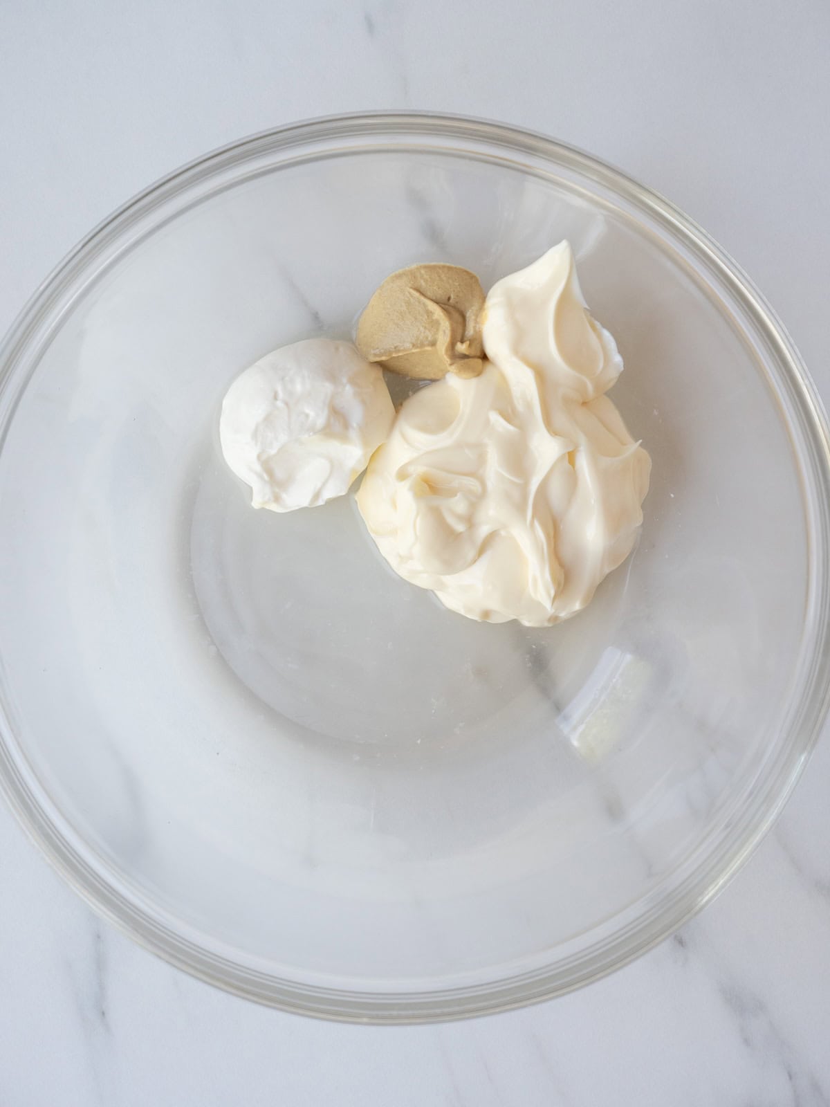 A mixing bowl with mayonnaise, sour cream, Dijon mustard and white wine vinegar.