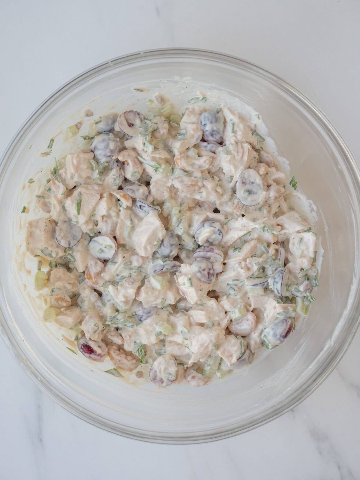 A mixing bowl with a creamy herb chicken salad.