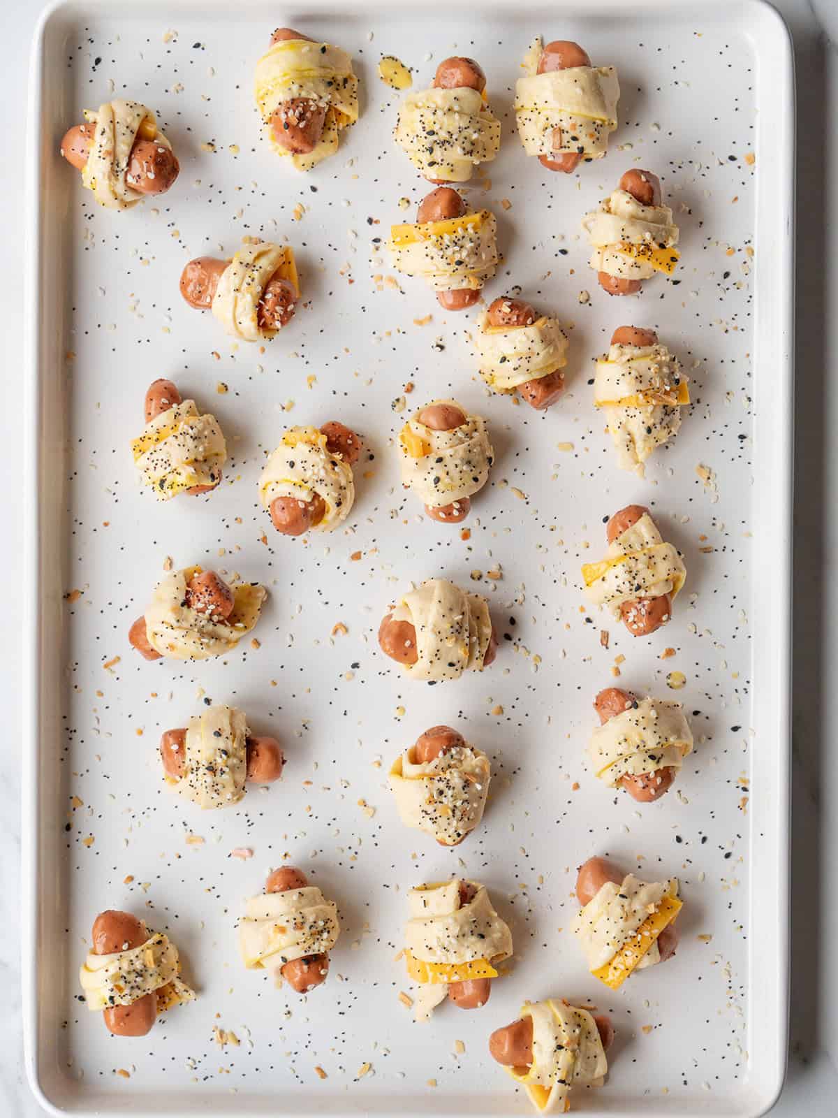 Unbaked Pigs in a Blanket brushed with egg wash and everything bagel seasoning