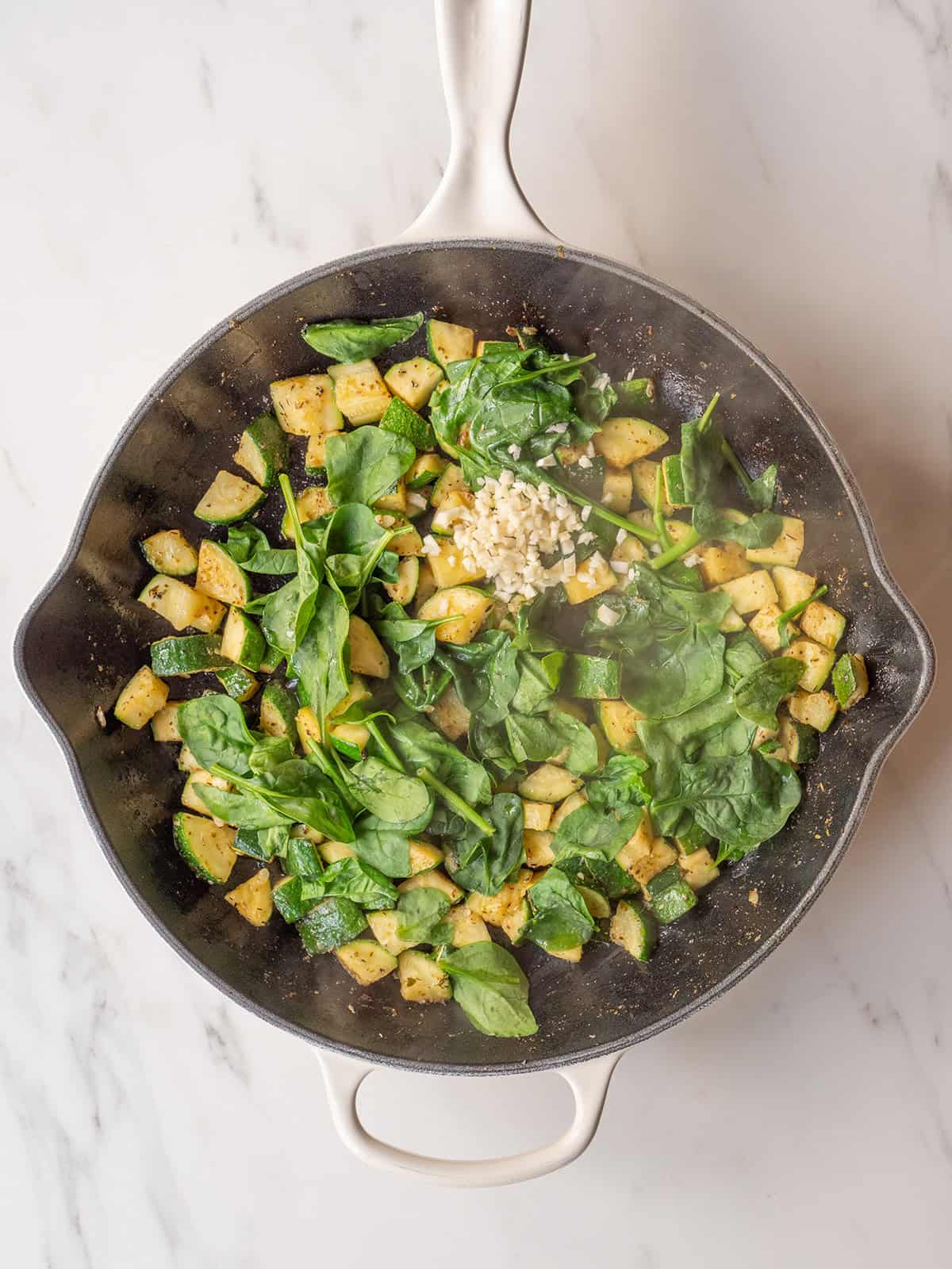 Wilted spinach, cooked zucchini, and chopped garlic in a large skillet