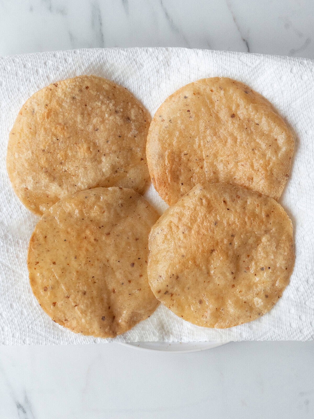 Fried corn tortillas on a paper towel lined plate for Huevos Rancheros