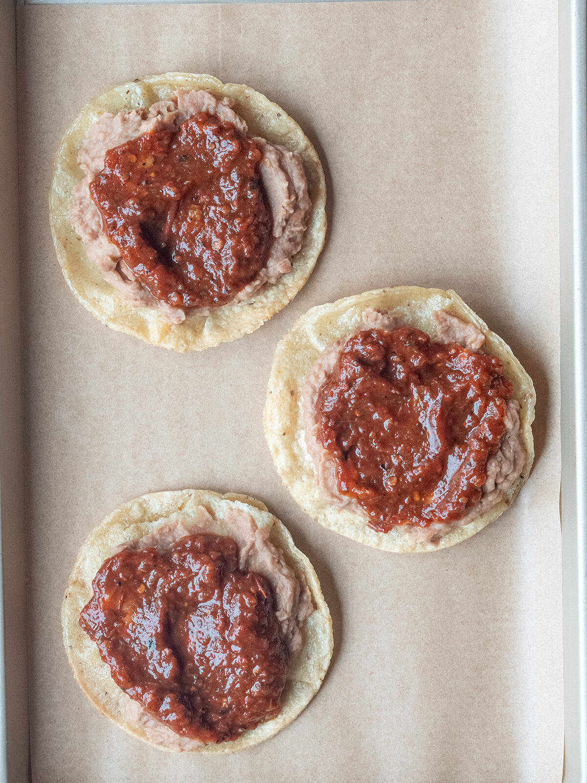 Chipotle salsa added to the top of Huevos Rancheros on a parchment lined tray