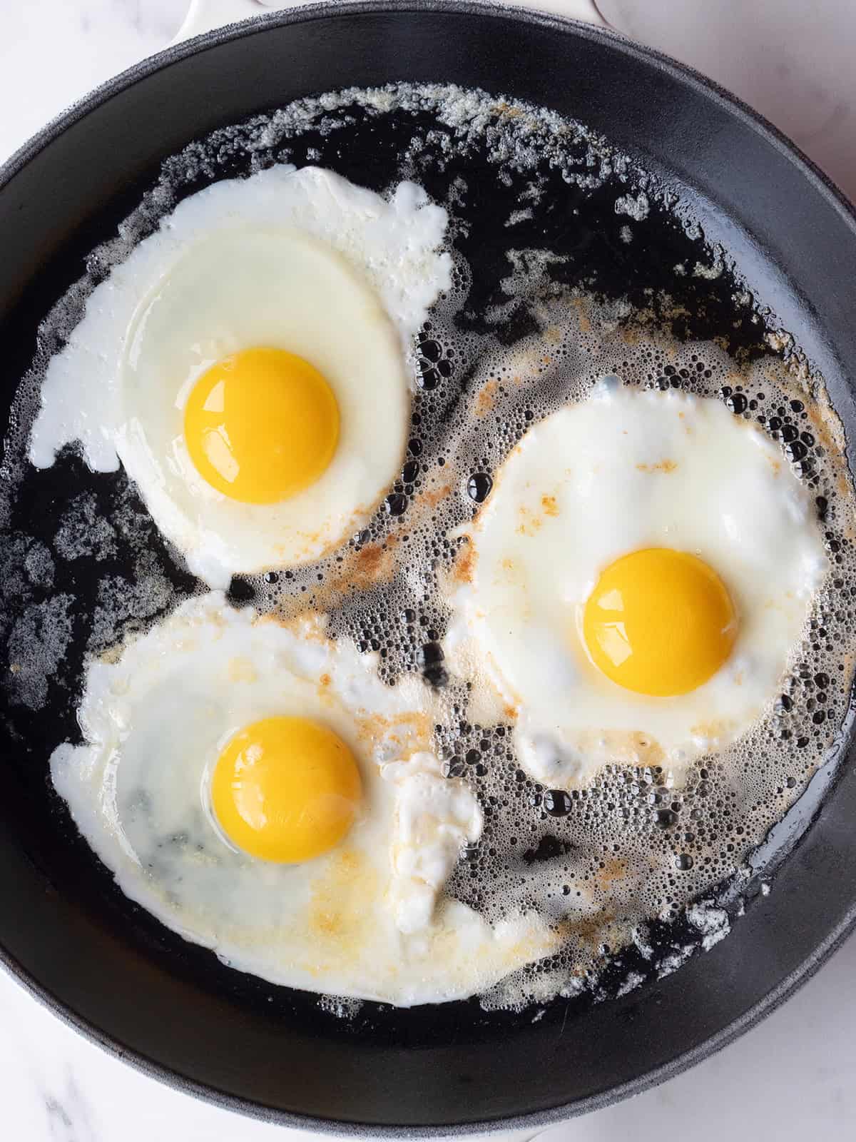 Eggs frying in a cast iron skillet