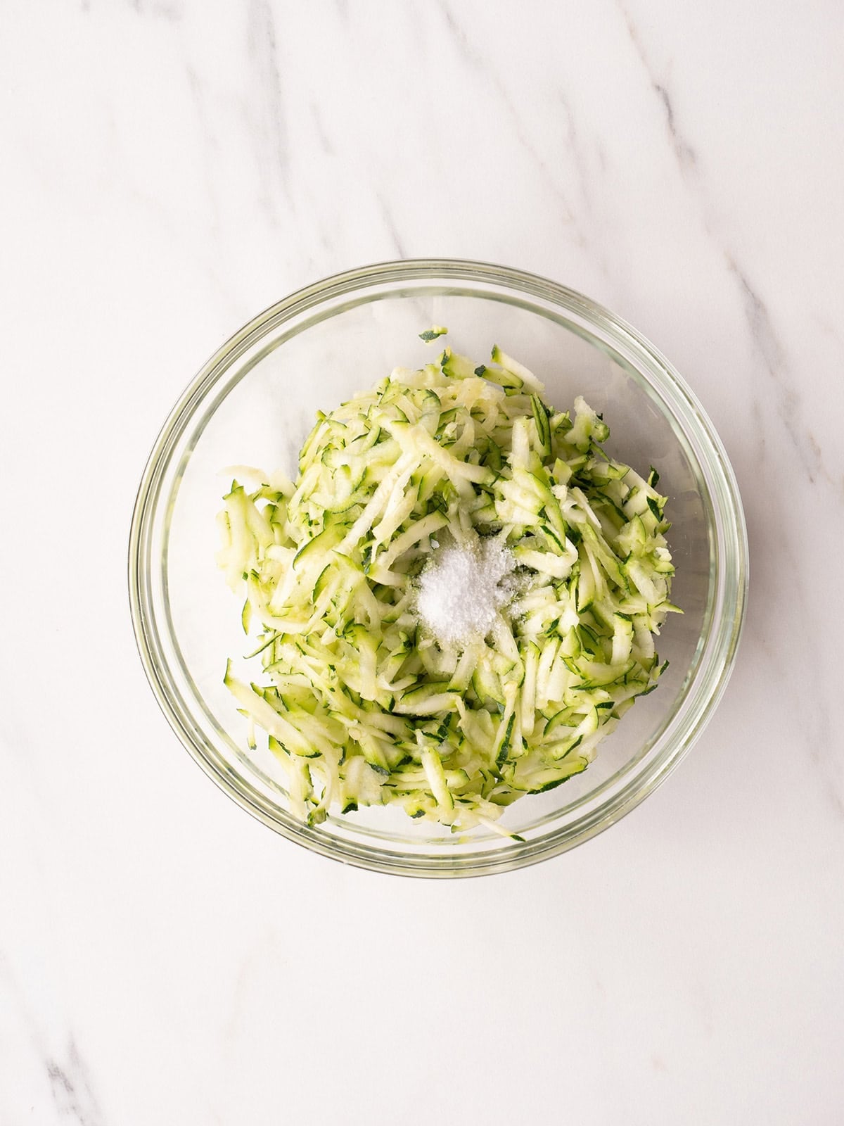 Shredded zucchini with salt in bowl