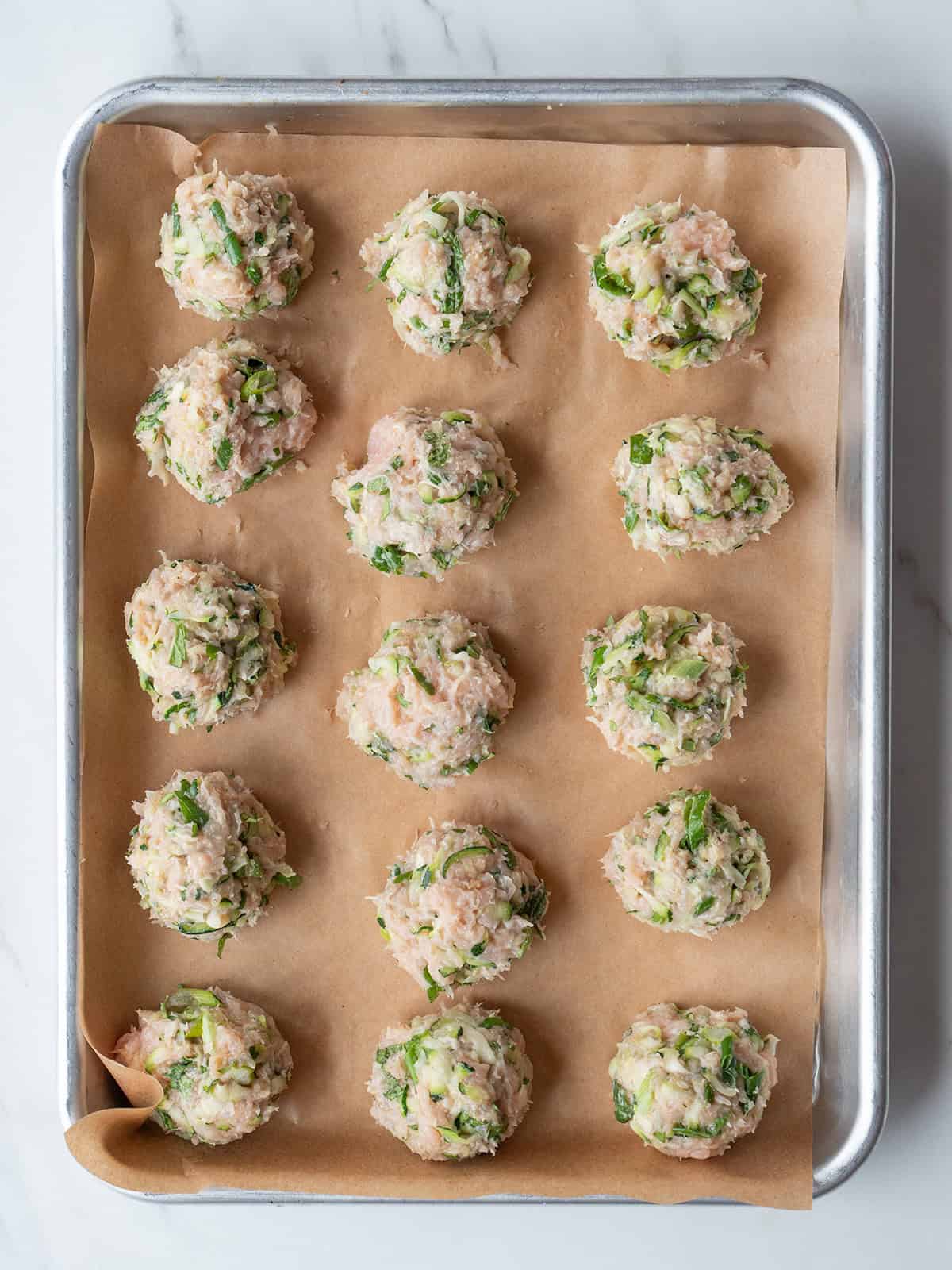 Raw chicken meatballs on parchment paper