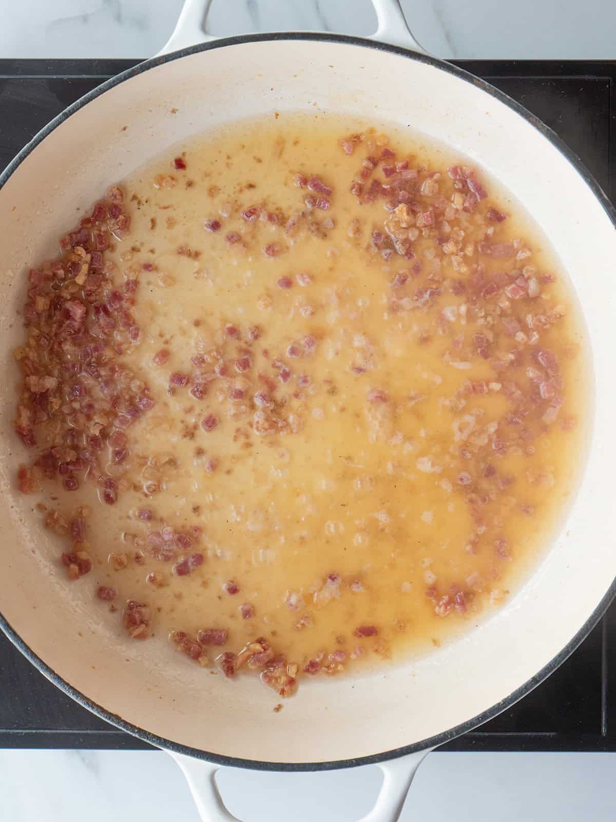Browning pancetta in a skillet.