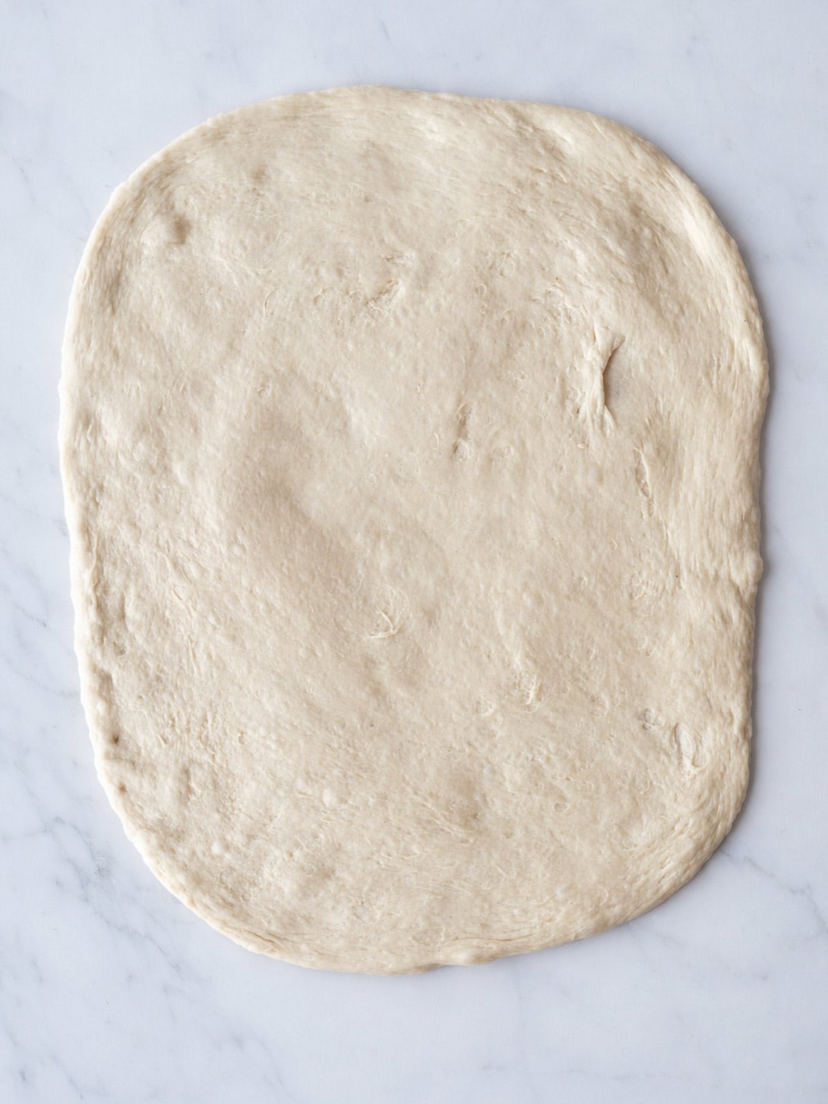 Raw pizza dough on marble surface