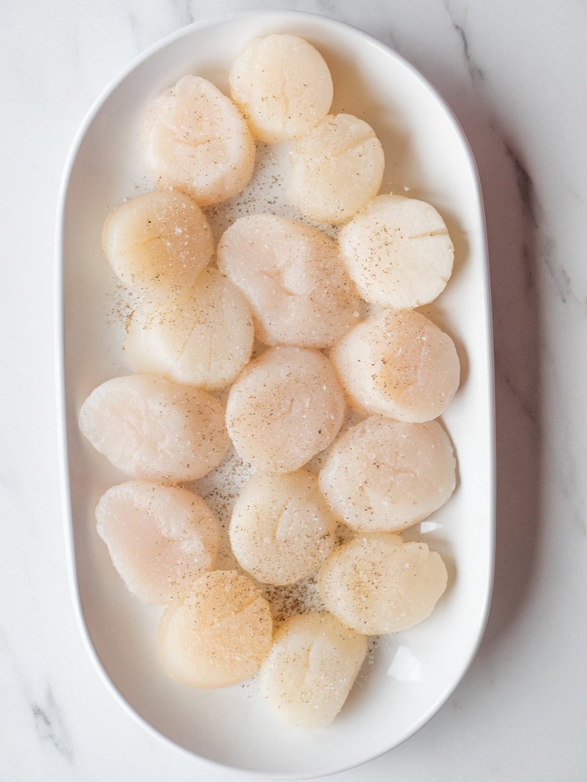 Raw scallops arranged on a platter.