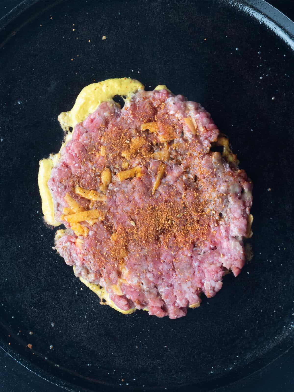 Raw burger patty on a skillet