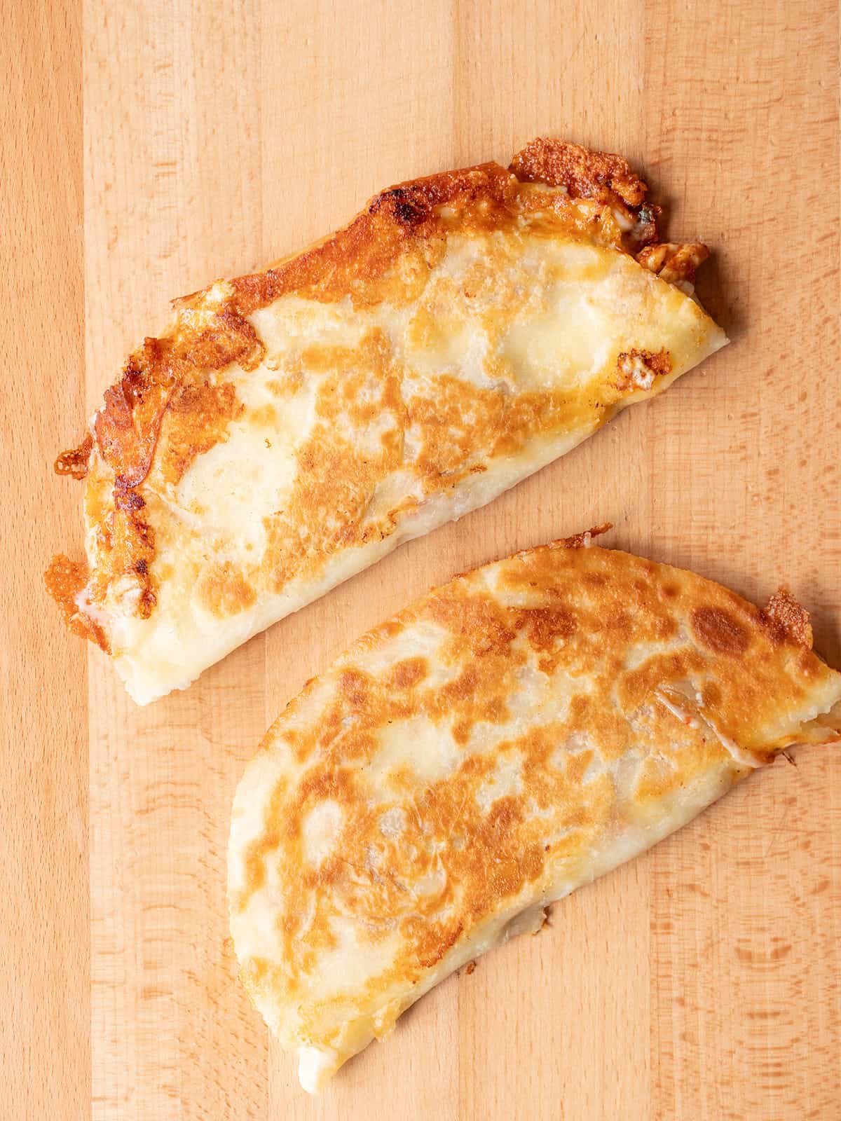 Two golden brown quesadillas on wood