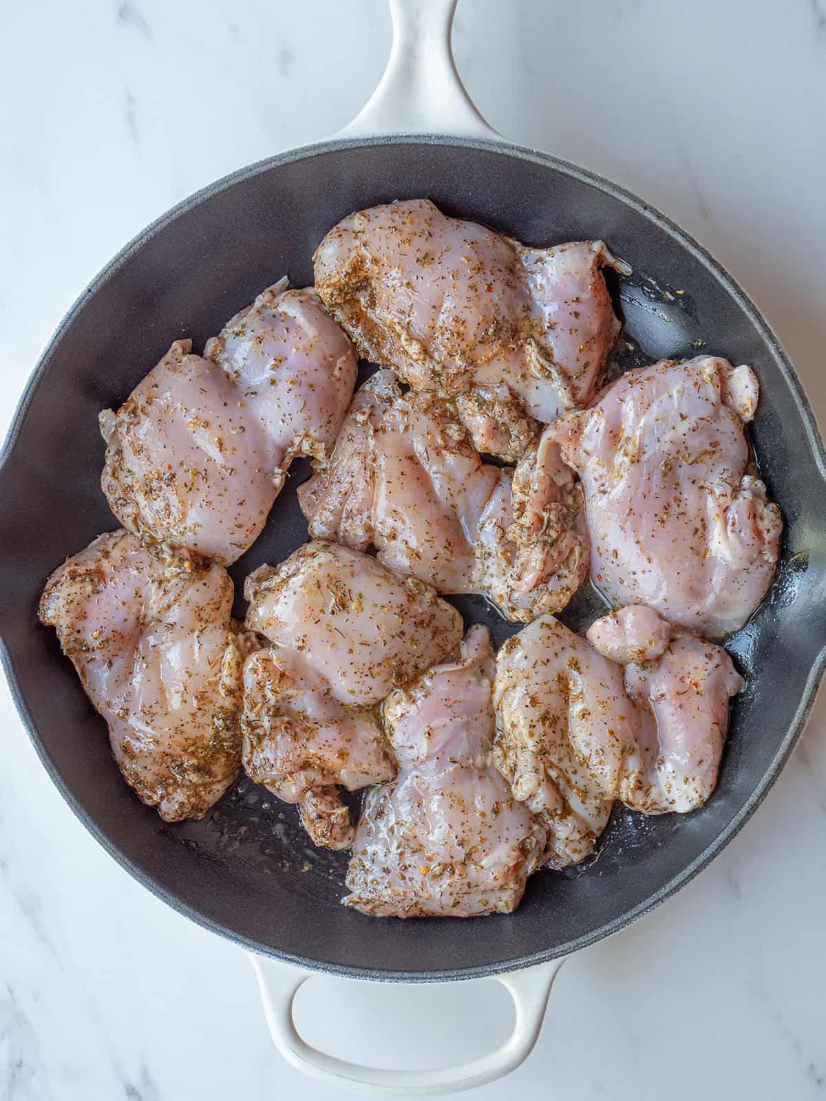 Raw chicken thighs in a skillet