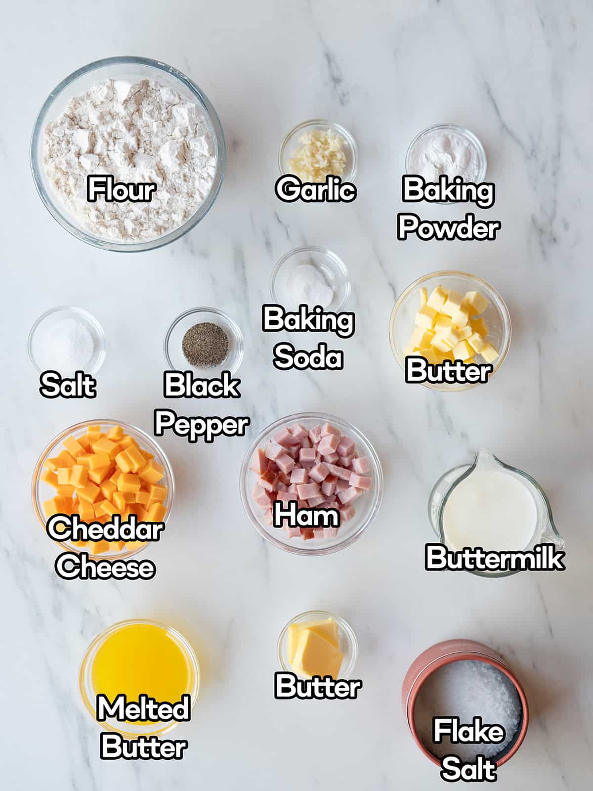 Ingredients for homemade Ham and Cheese Biscuits, including flour, cheddar, ham, butter, and buttermilk.