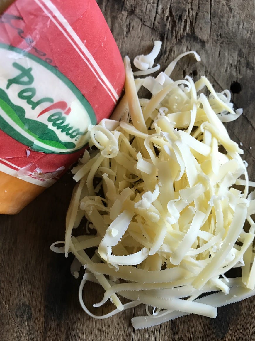 A block of Parrano cheese with some of the shredded cheese next to it.