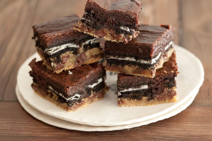 A pile of 5 slutty brownies sitting on top of 2 stacked dishes.  